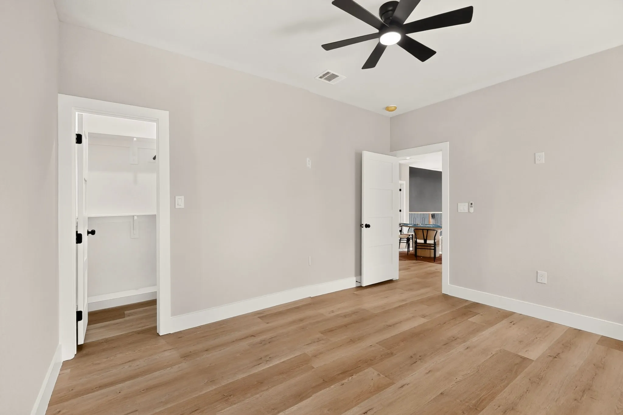 Wood-finish flooring, white trim, and a black ceiling fan