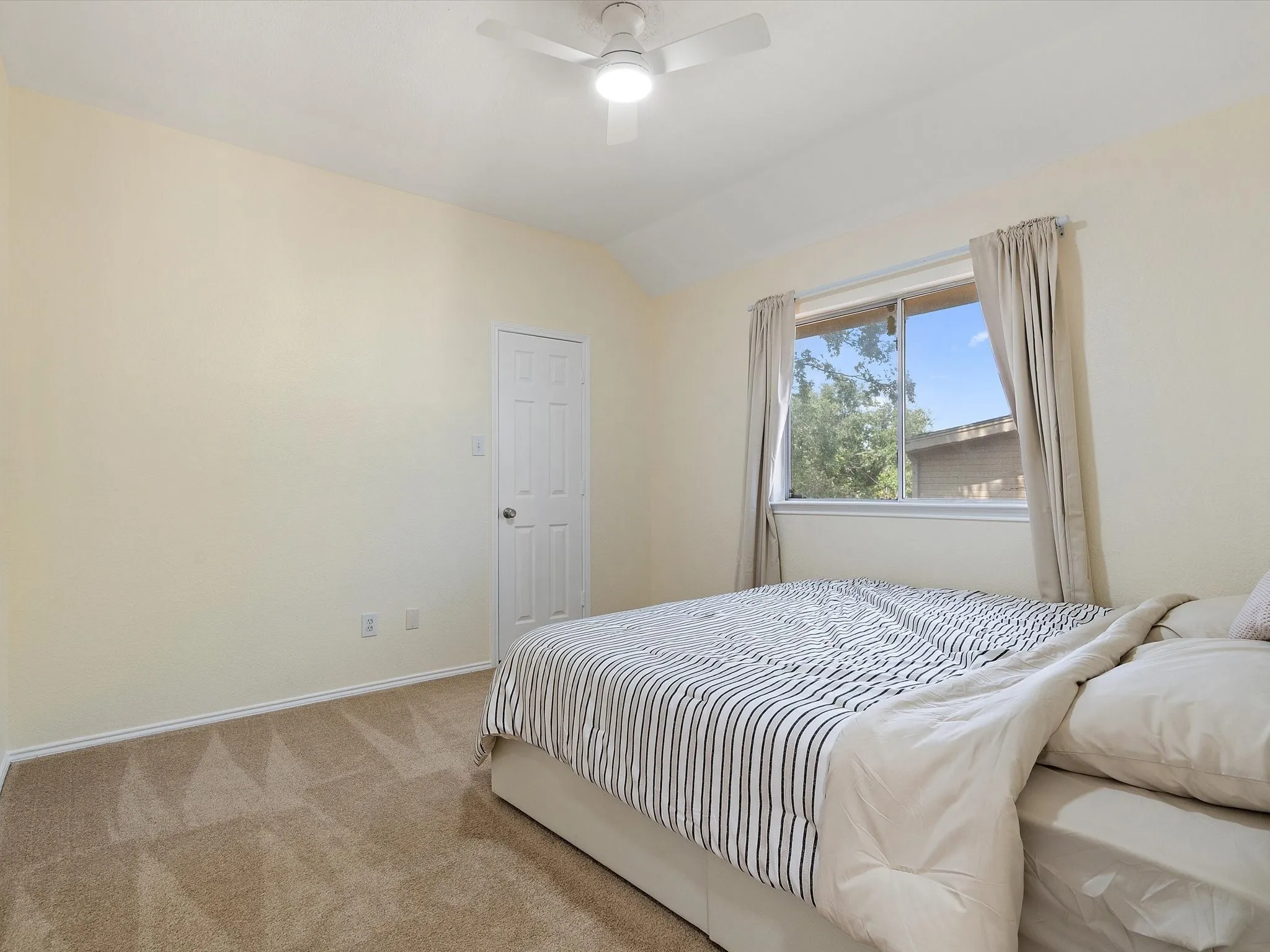 Bedroom featuring carpet floors, vaulted ceiling, and a ceiling fan