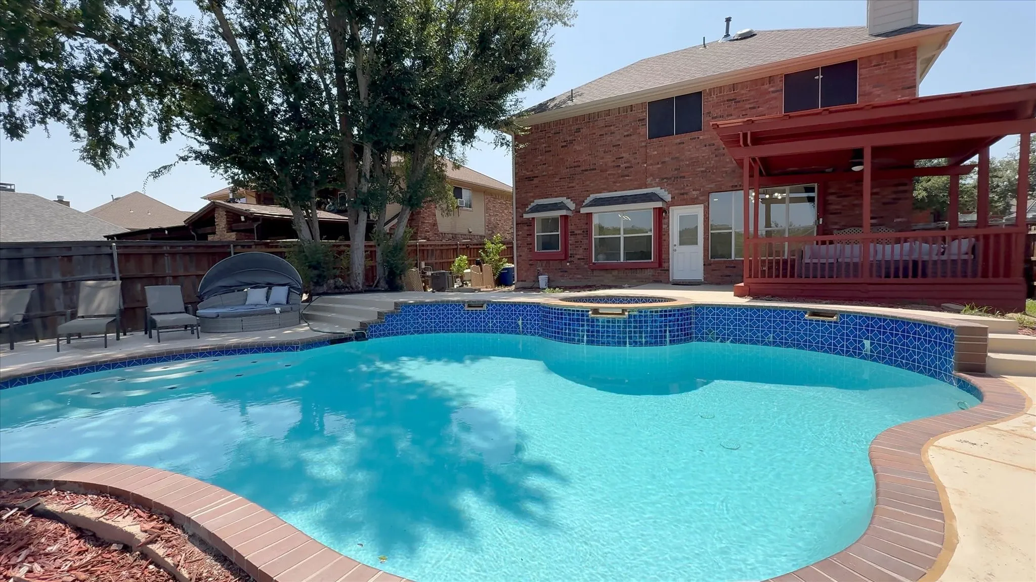 Resort-style backyard featuring a freeform swimming pool with integrated spa and patterned blue tile