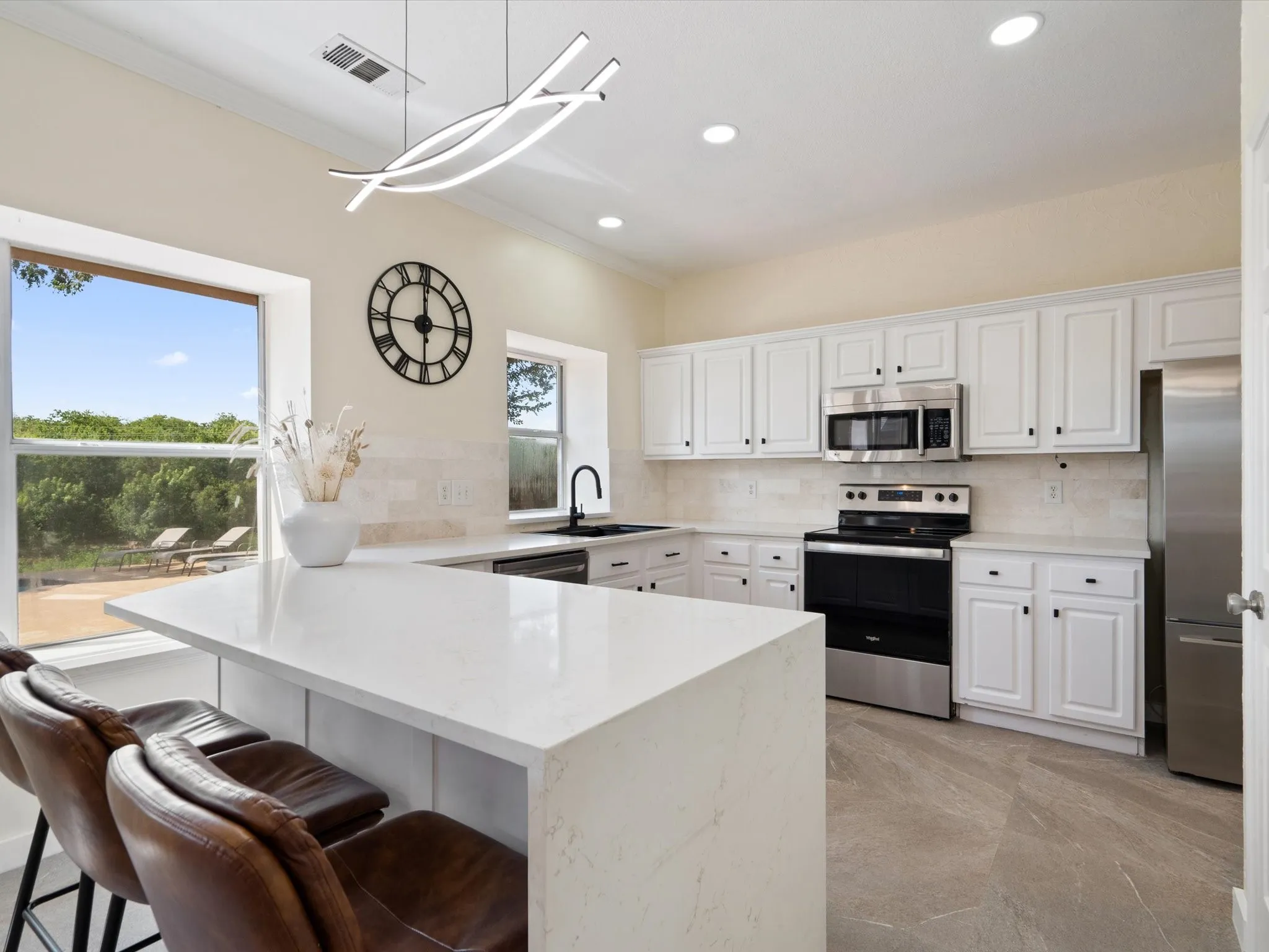 Kitchen with decorative backsplash, a peninsula, appliances with stainless steel finishes, a breakfast bar area, and ornamental molding