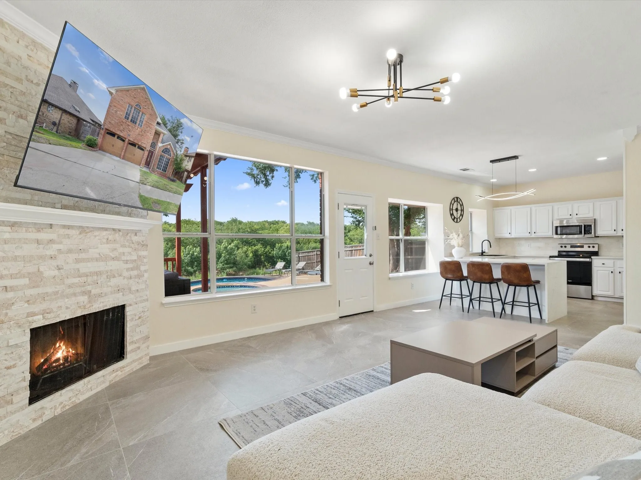 Living room with crown molding, a stone fireplace, a chandelier, and recessed lighting