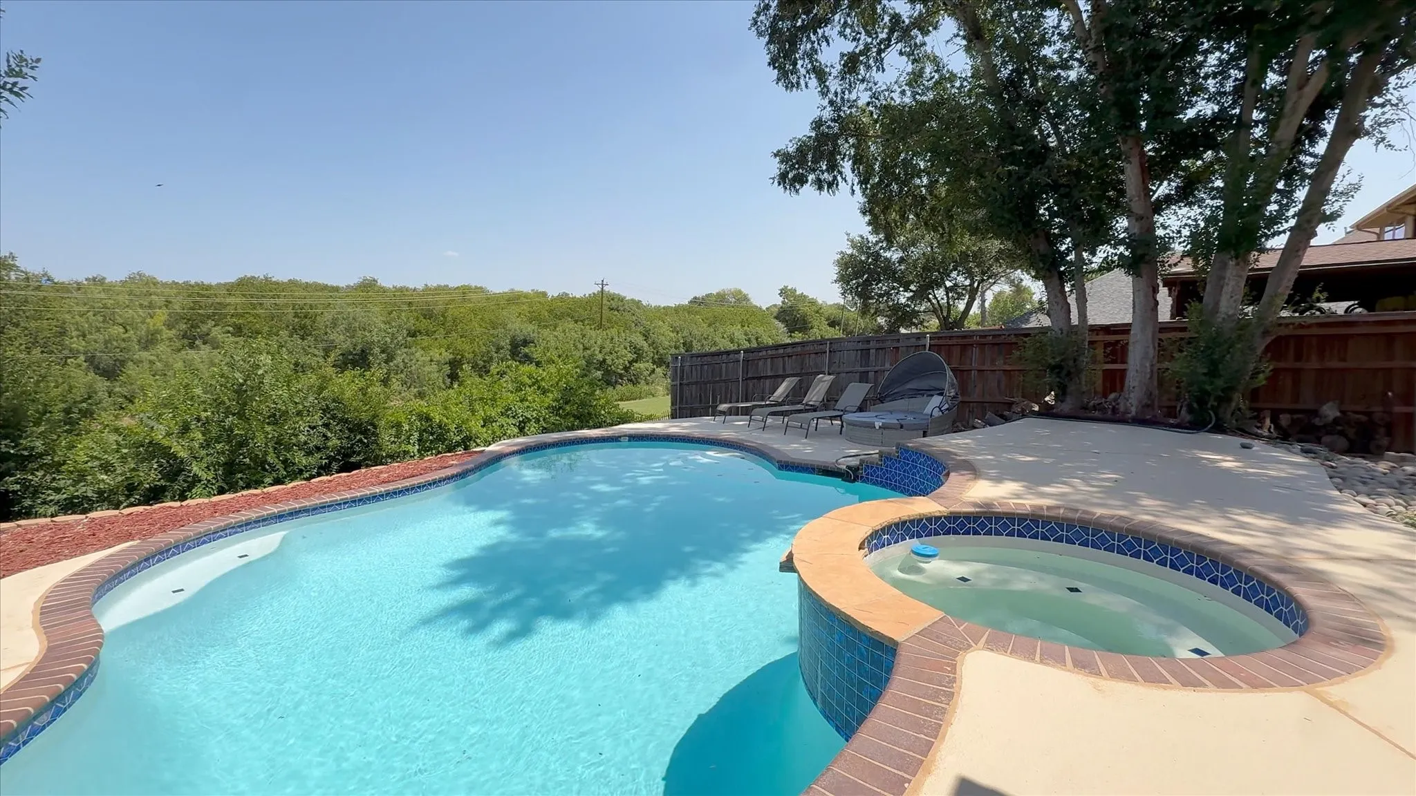 Outdoor swimming pool with integrated spa and concrete surround