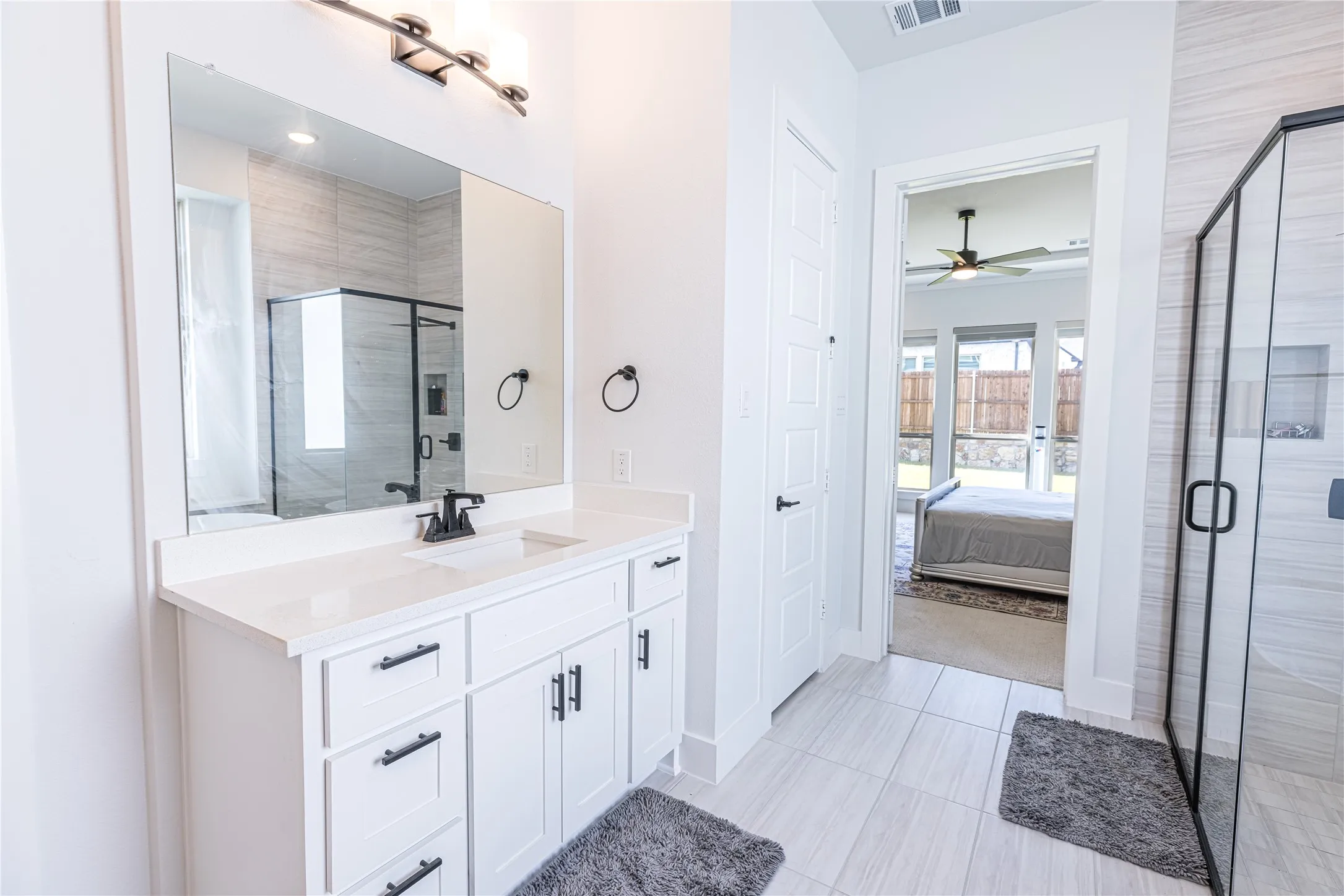 Bathroom with a white vanity featuring a single sink, black faucet, and white countertop