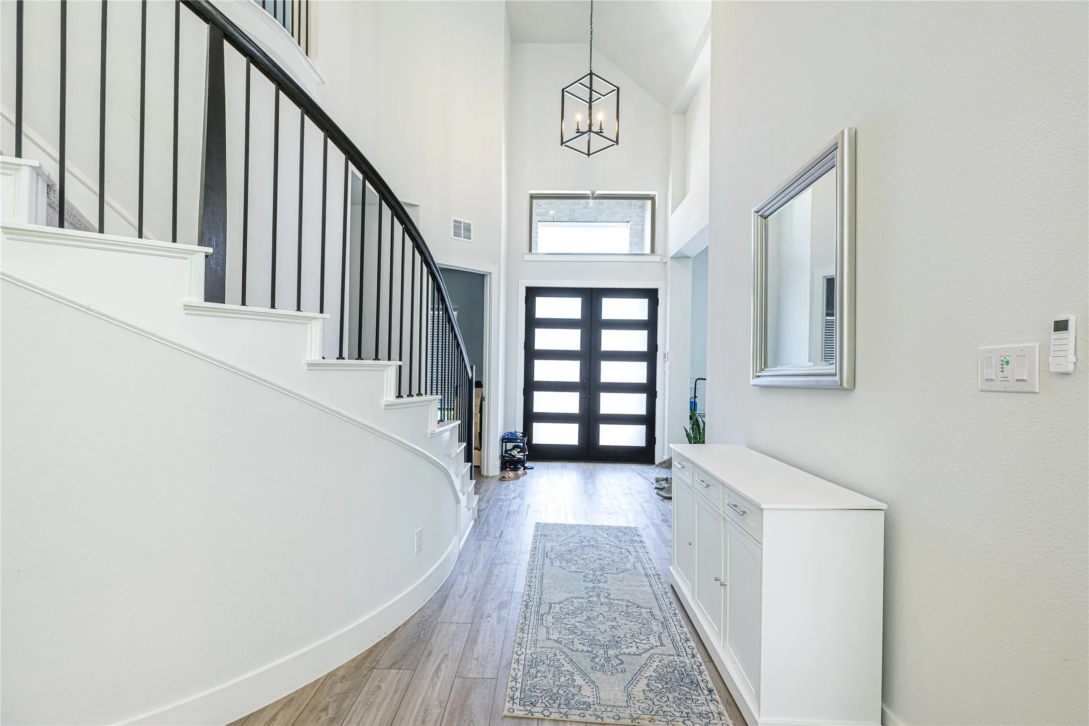 Entryway featuring a curved staircase with black metal balusters and white risers