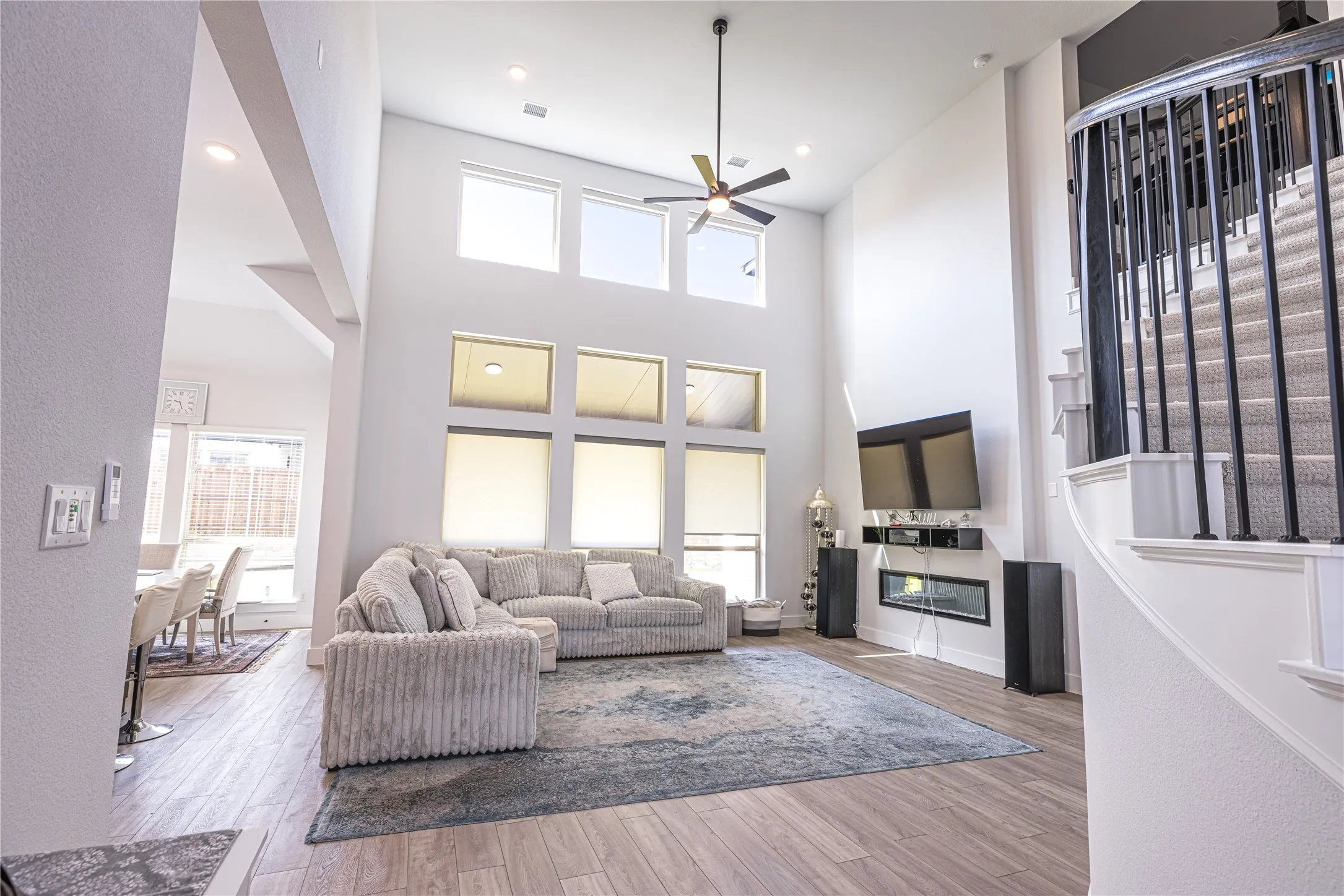 Open-concept living space featuring high ceilings, wood-finish flooring, and an integrated linear fireplace