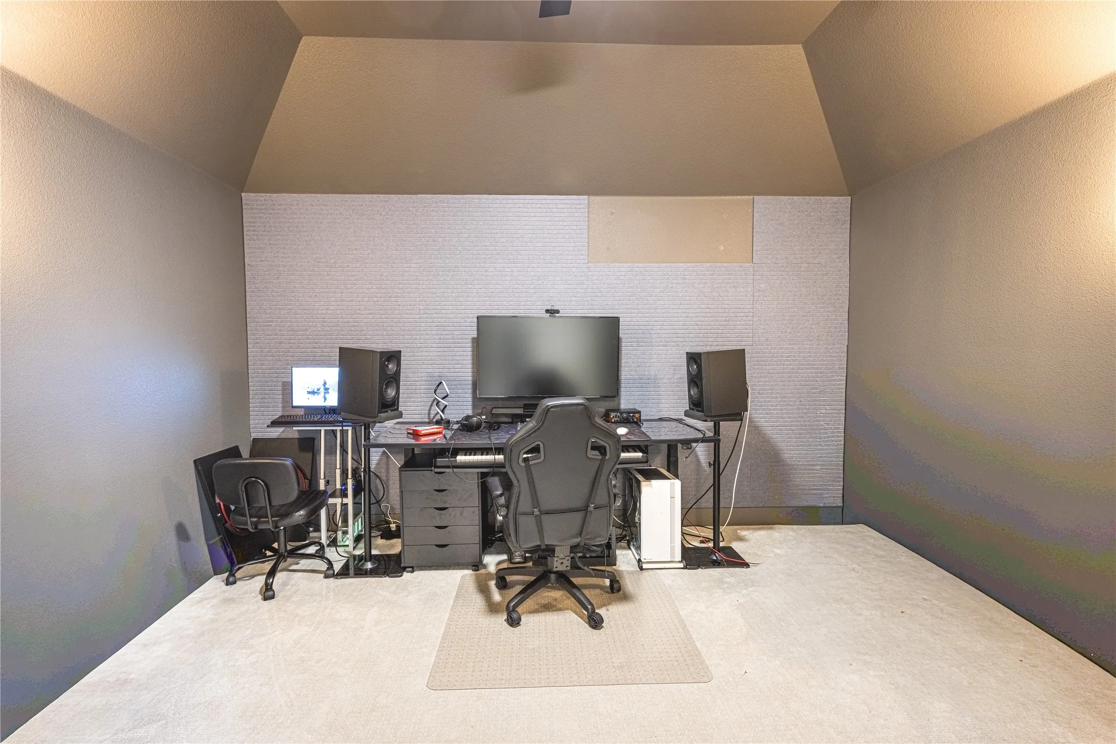 Room featuring sloped ceilings, light-colored carpeting, and a textured accent wall