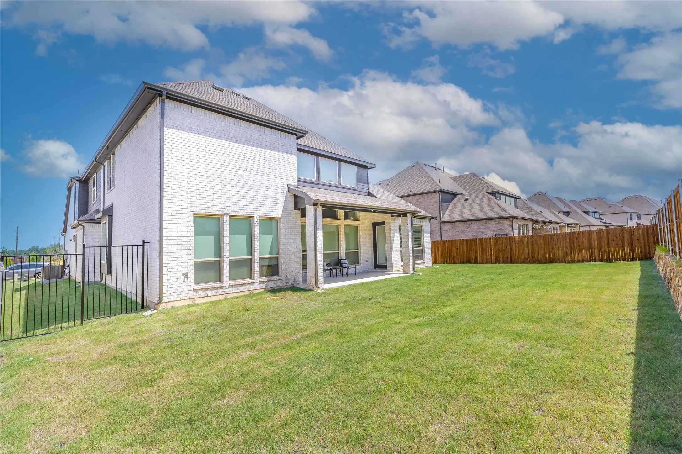 Expansive backyard featuring a large green lawn, covered patio, and privacy fencing