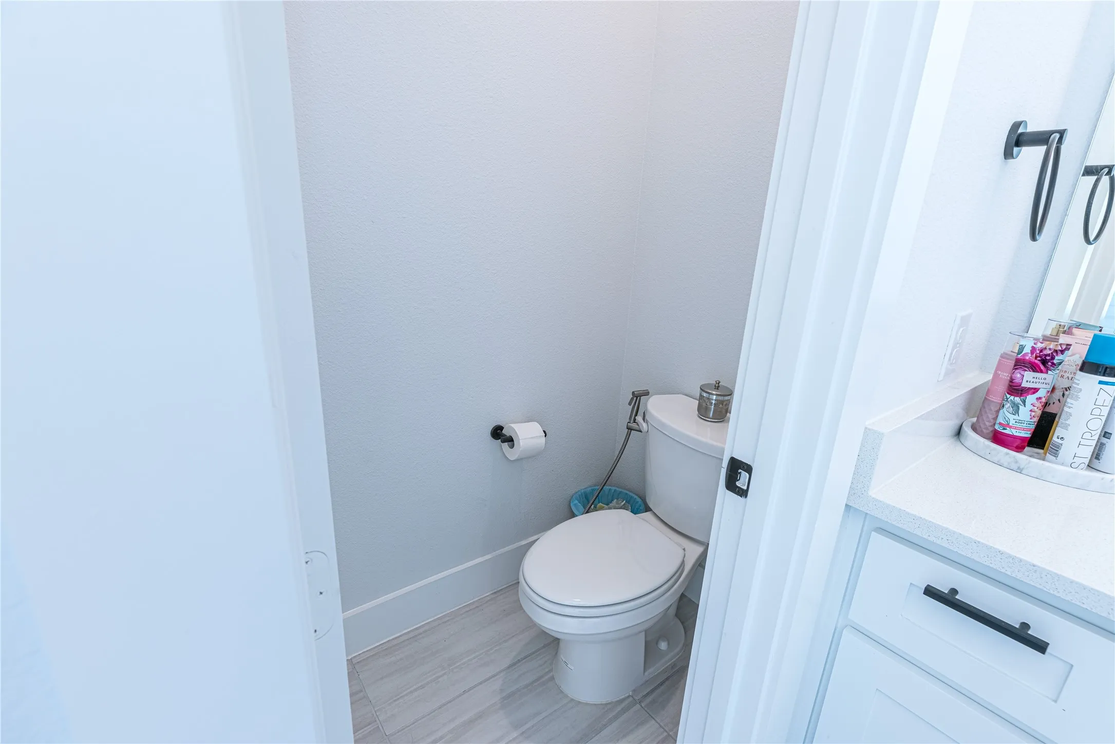 Dedicated water closet with a white toilet, bidet attachment, and wood-finish flooring
