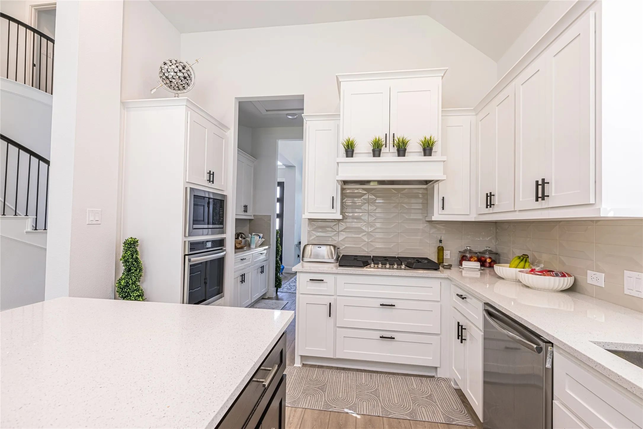 Modern kitchen featuring white shaker cabinetry, stainless steel appliances, a gas cooktop, light-toned countertops, and a textured tile backsplash