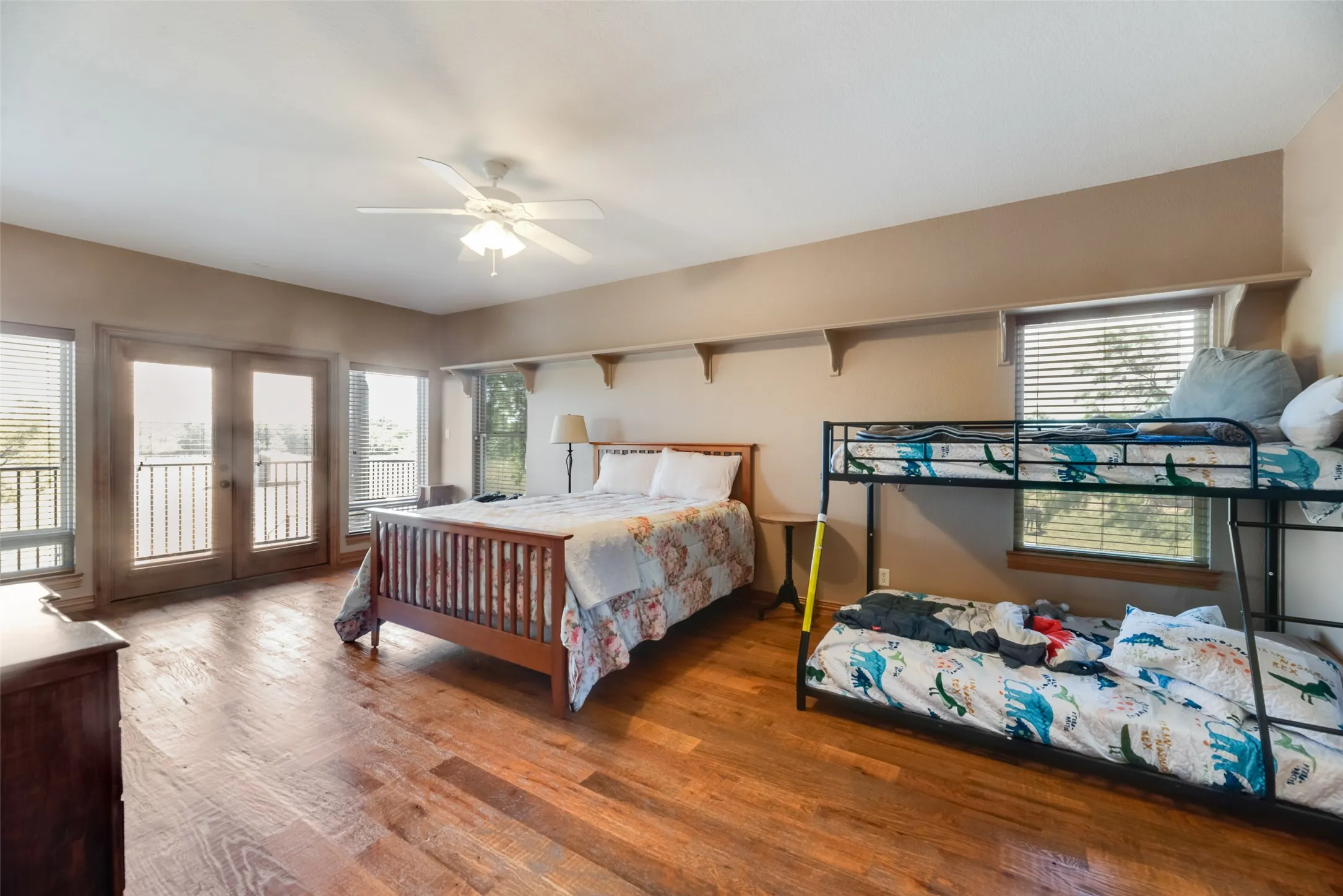 Spacious room featuring wood-finish flooring, light tan walls, and a ceiling fan with integrated lighting