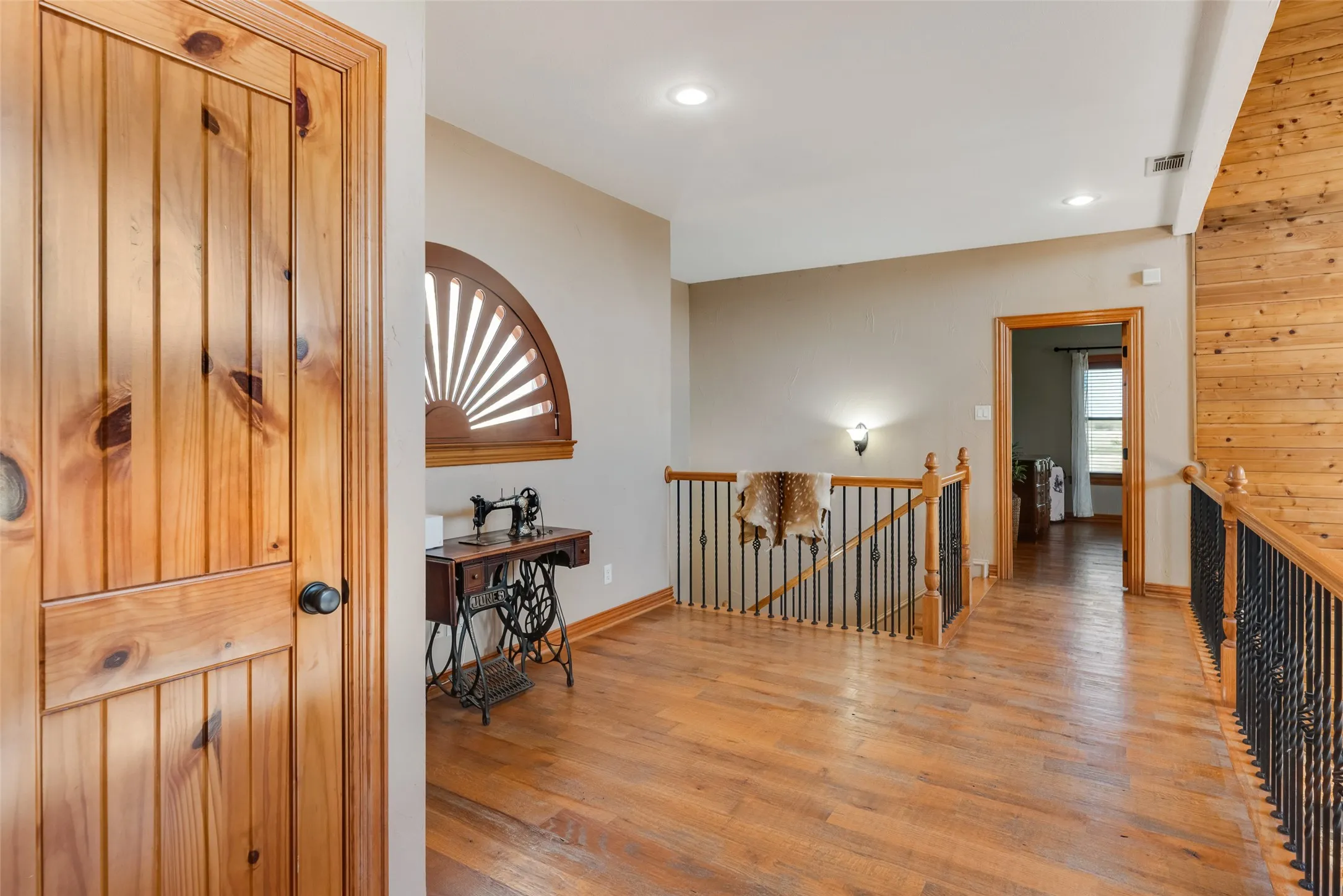 Spacious 2nd level  hallway featuring wood-finish flooring, a decorative arched window, recessed lighting, and a wood-paneled ceiling accent