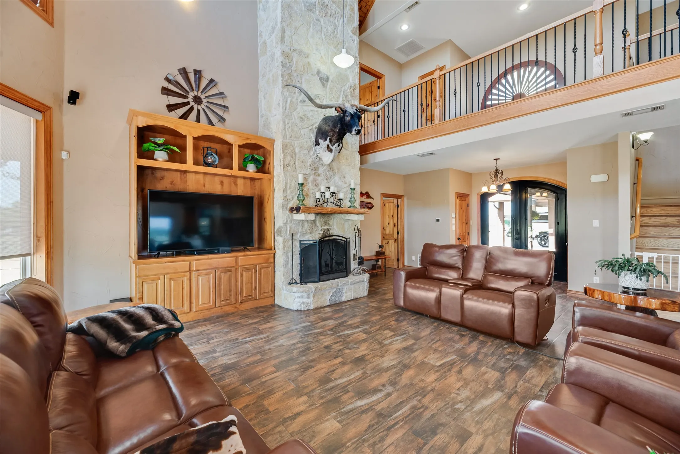 Expansive living area featuring wood-finish flooring and a two-story stone fireplace