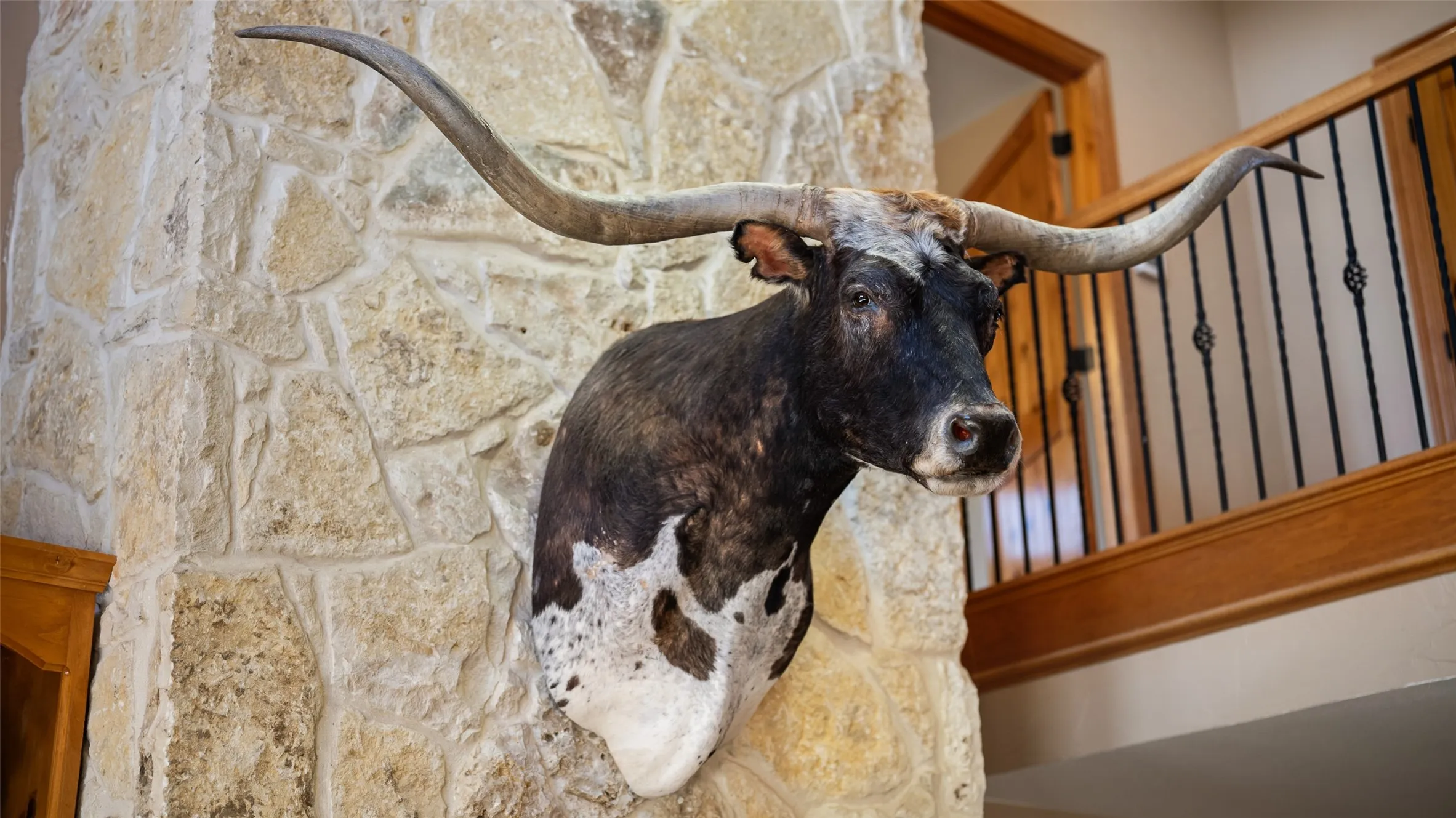 Stone masonry column featuring a wood-finish railing with wrought iron balusters