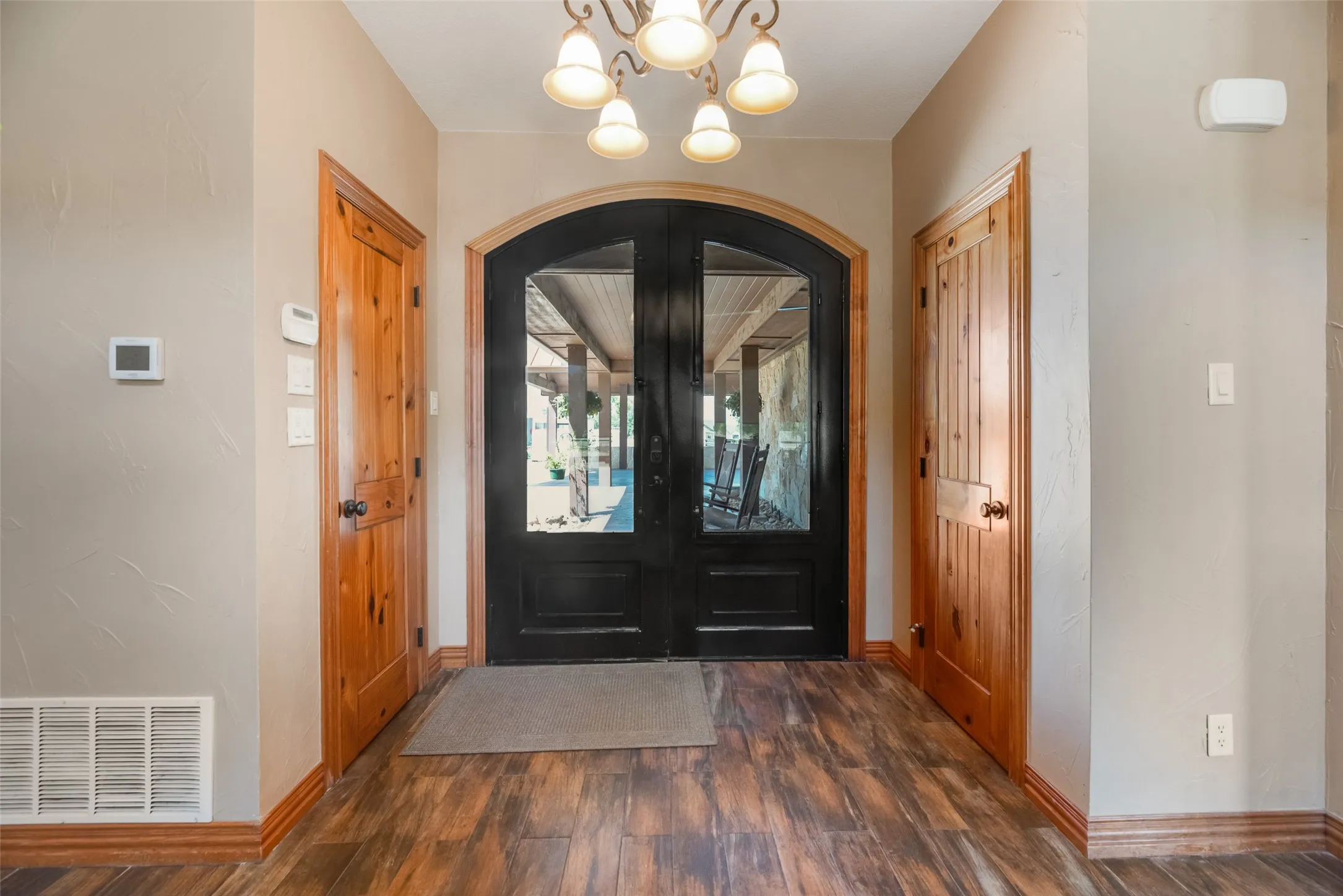 Arched double entry doors with dark framing and glass panels