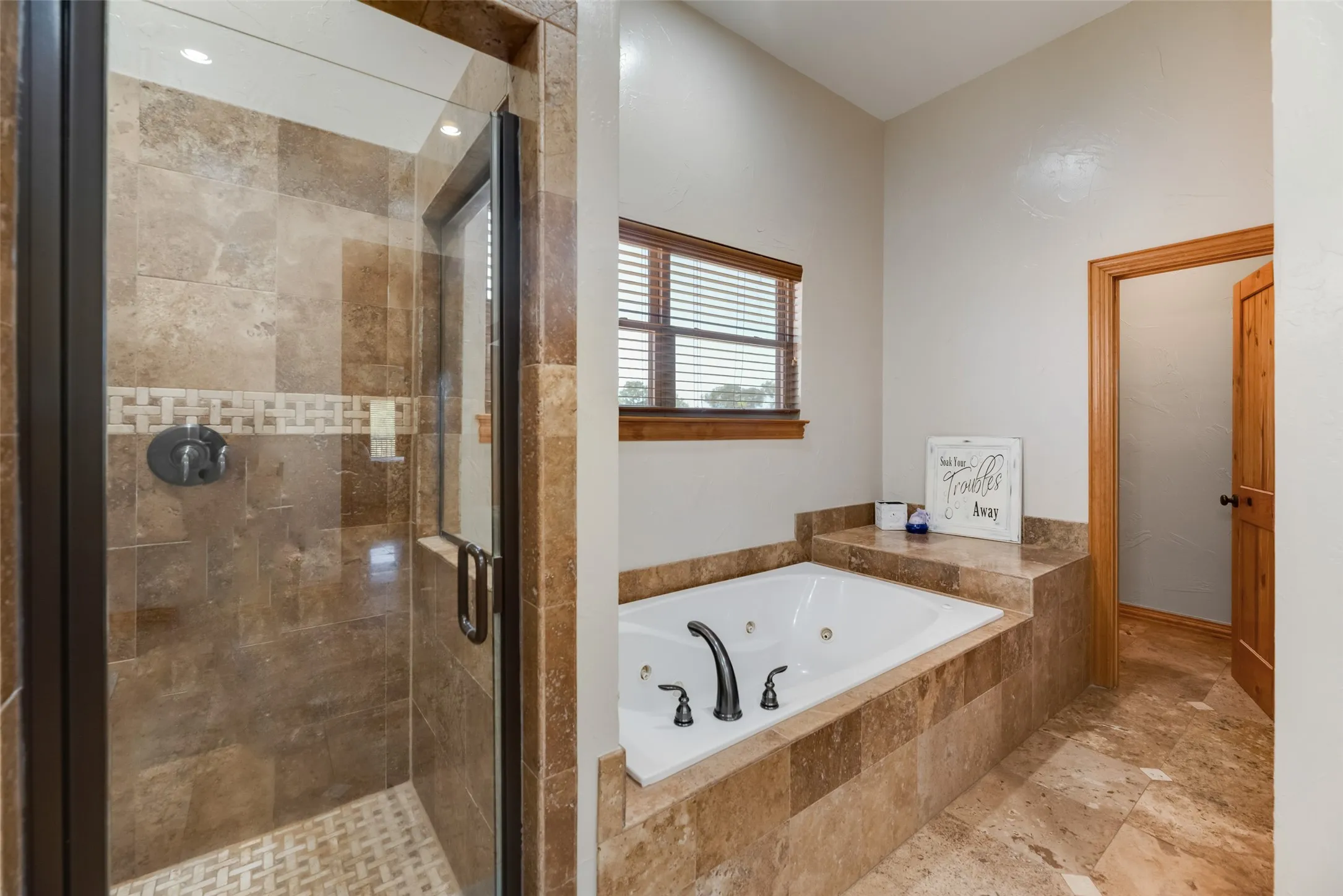 Bathroom featuring a walk-in shower with glass enclosure, built-in jetted tub, and stone tile flooring