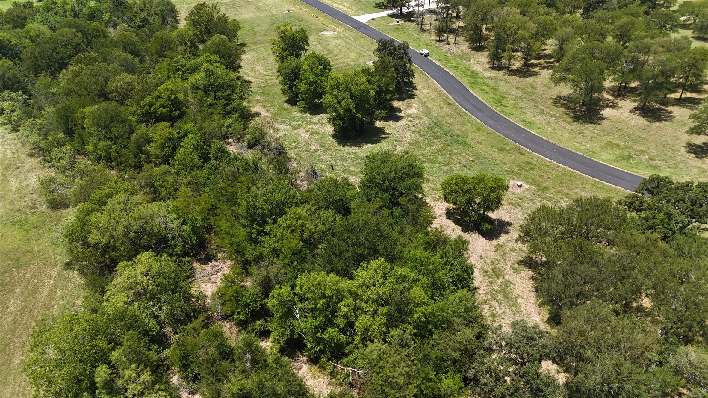 Aerial vantage point showing the custom homesite nestled along a low-traffic paved private road.