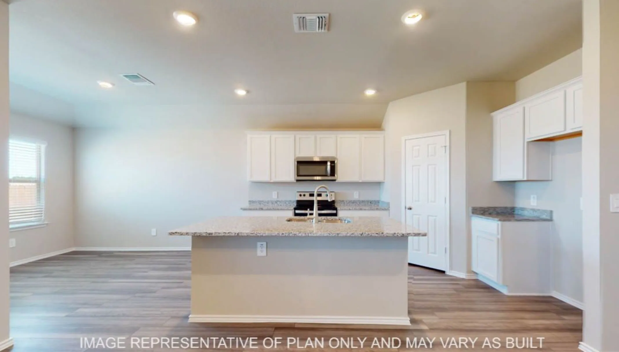 Open concept kitchen featuring a central island with a sink, white cabinetry, integrated stainless steel microwave, and wood-finish flooring
