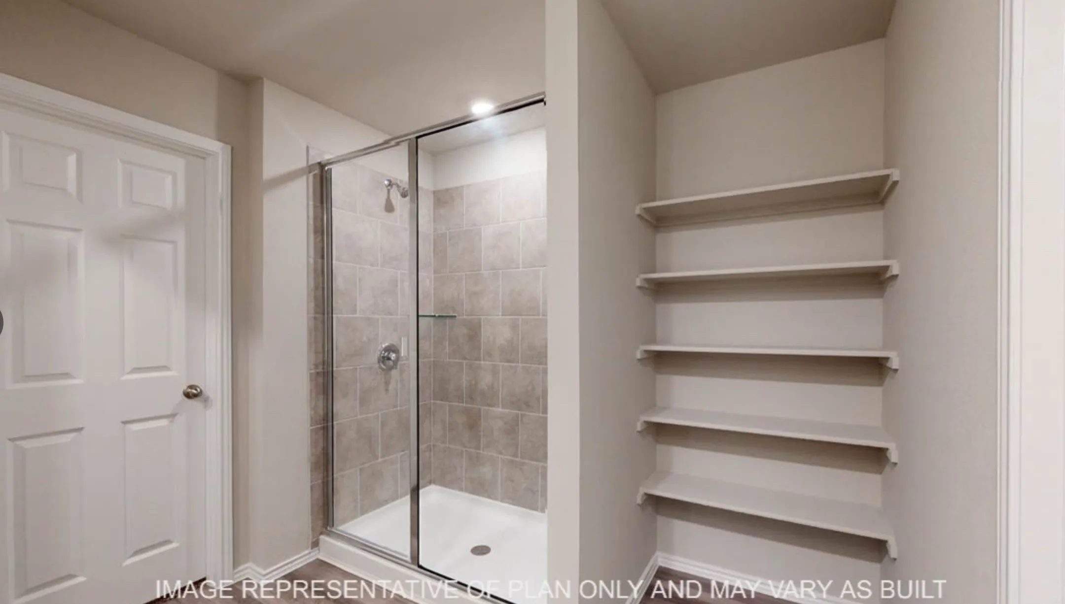 Walk-in shower with tiled surround and glass enclosure, complemented by recessed shelving for storage