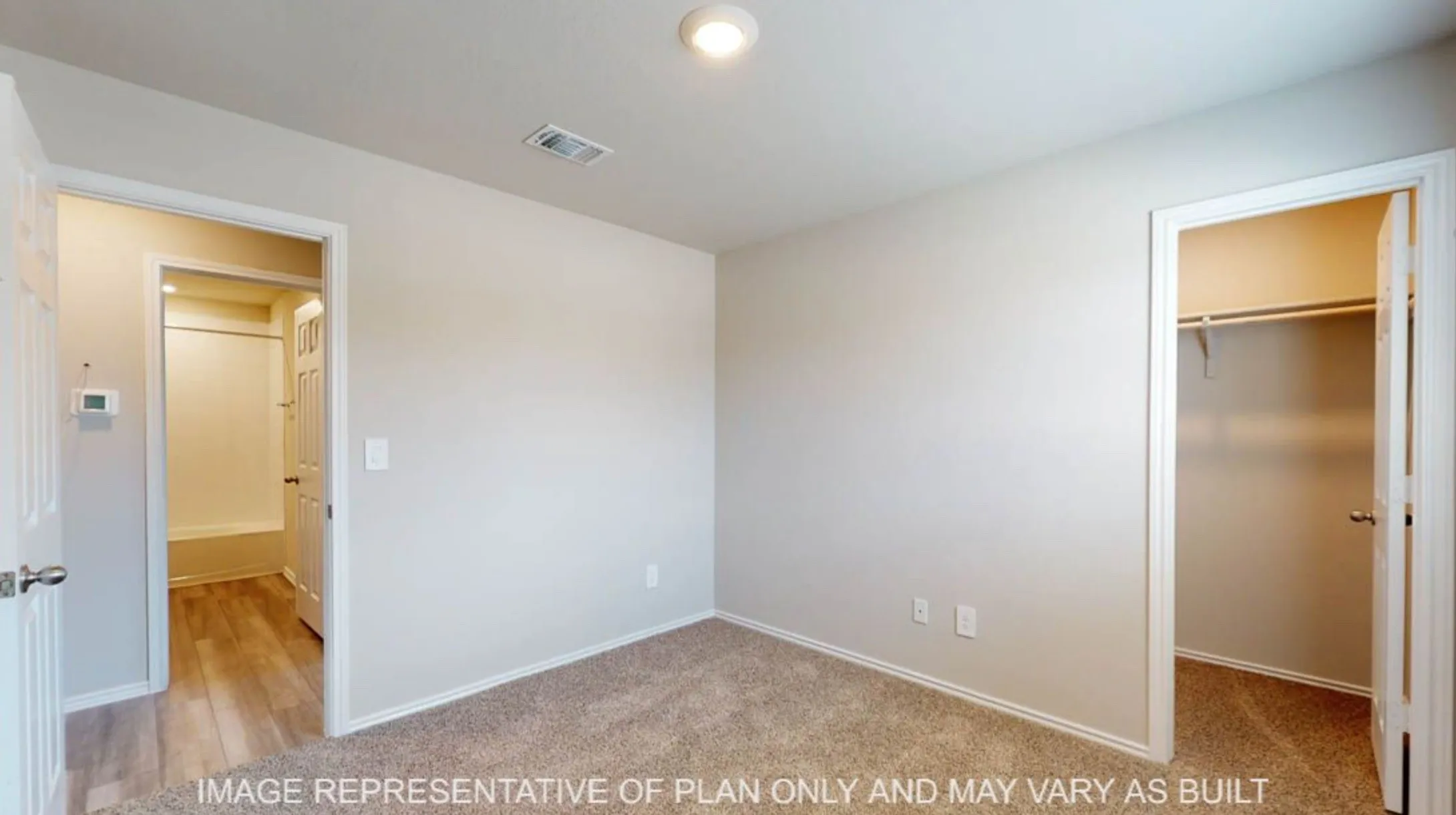 Neutral tone wall paint, carpet flooring, recessed lighting, and a built-in closet with shelving and hanging rod