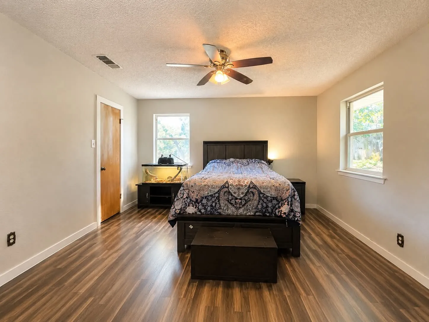 Spacious room featuring wood-finish flooring, light neutral wall paint, and two single-pane windows