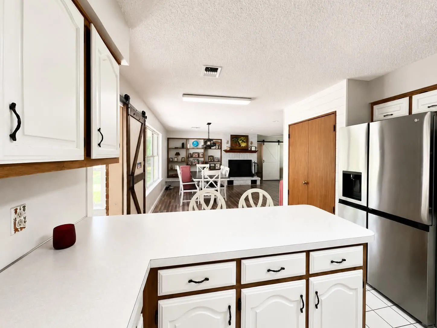 Kitchen island with white countertop and white cabinetry with black hardware