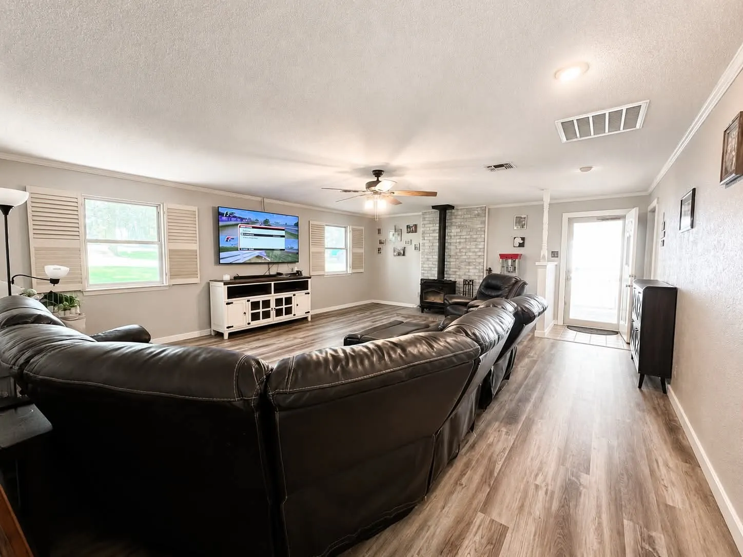 Spacious living area featuring wood-finish flooring and a wood-burning stove with a brick-style surround