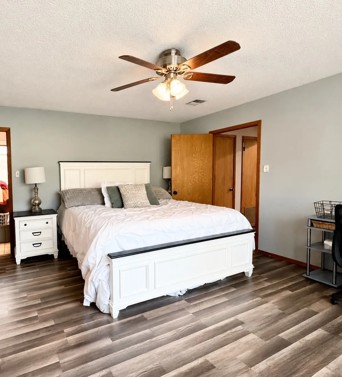 Spacious room featuring wood-finish flooring, a ceiling fan with integrated lighting, and a neutral wall color