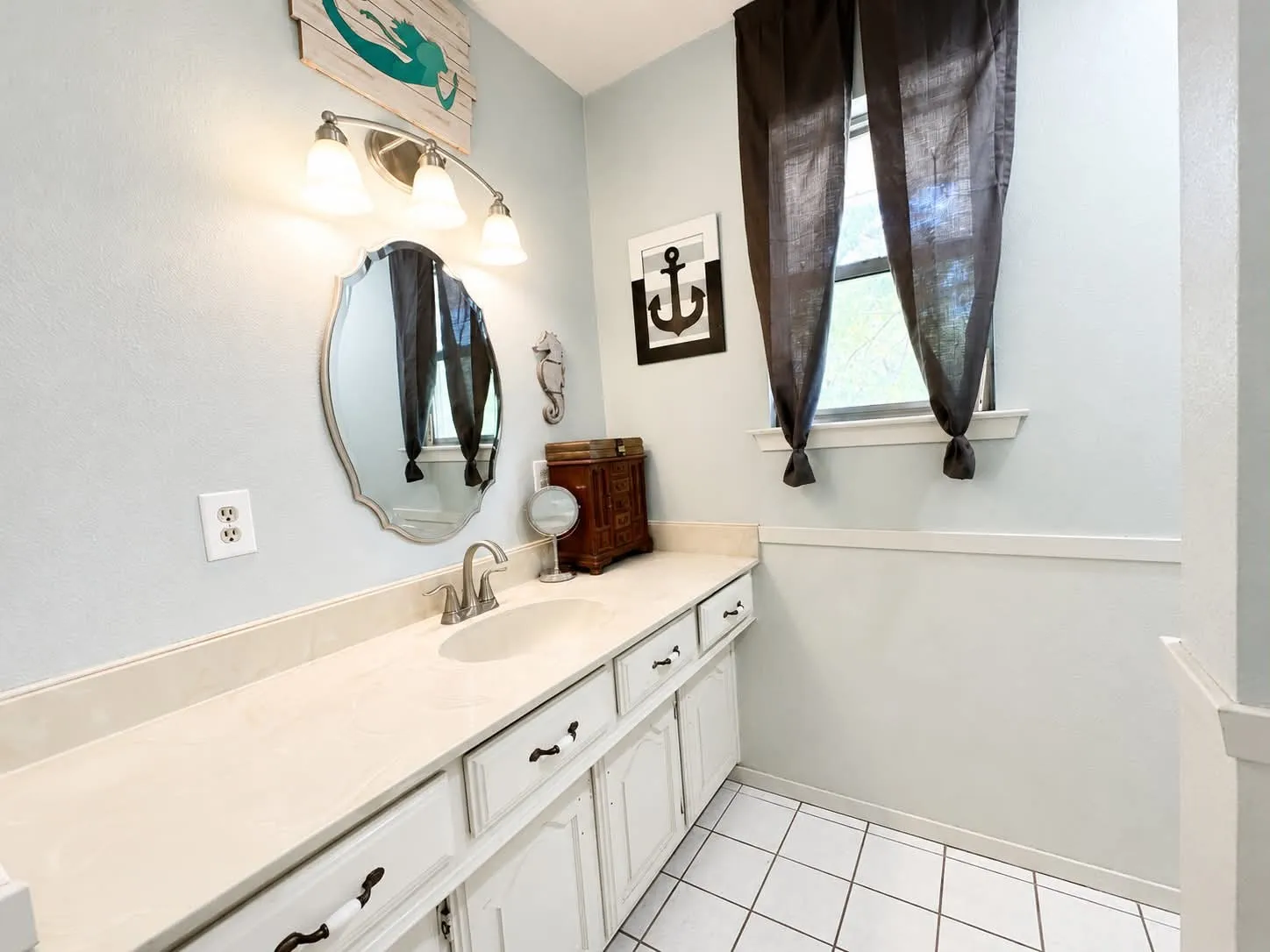 Bathroom featuring a white vanity with extensive counter space, an integrated sink, and brushed nickel hardware