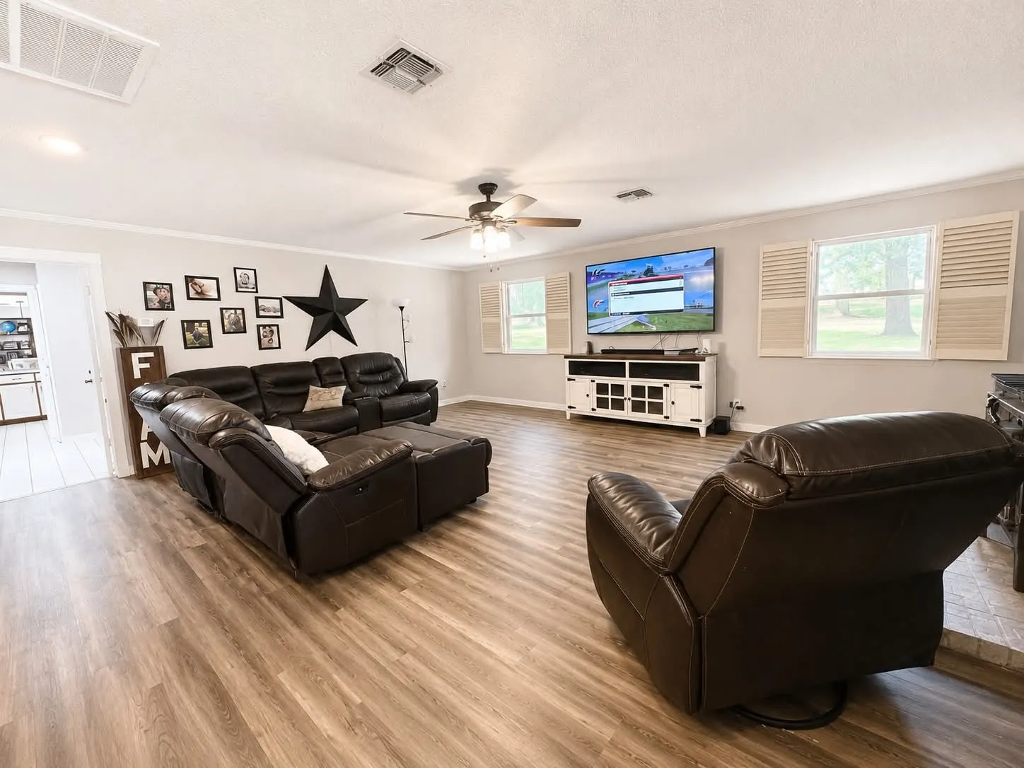 Spacious living area featuring wood-finish flooring, light gray walls, white trim, and a ceiling fan