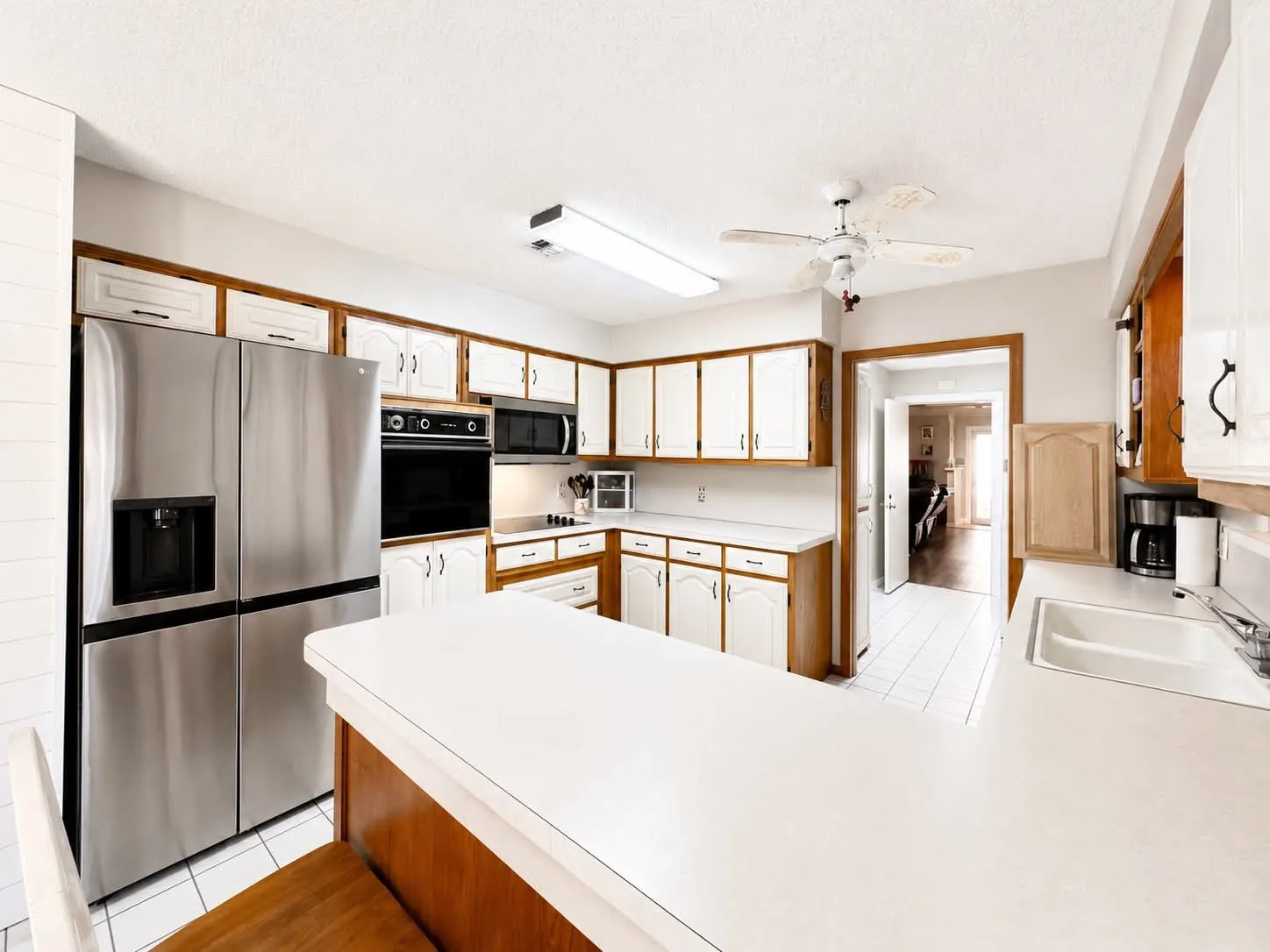 Kitchen featuring white cabinetry with wood trim, stainless steel appliances, a built-in oven, and white countertops