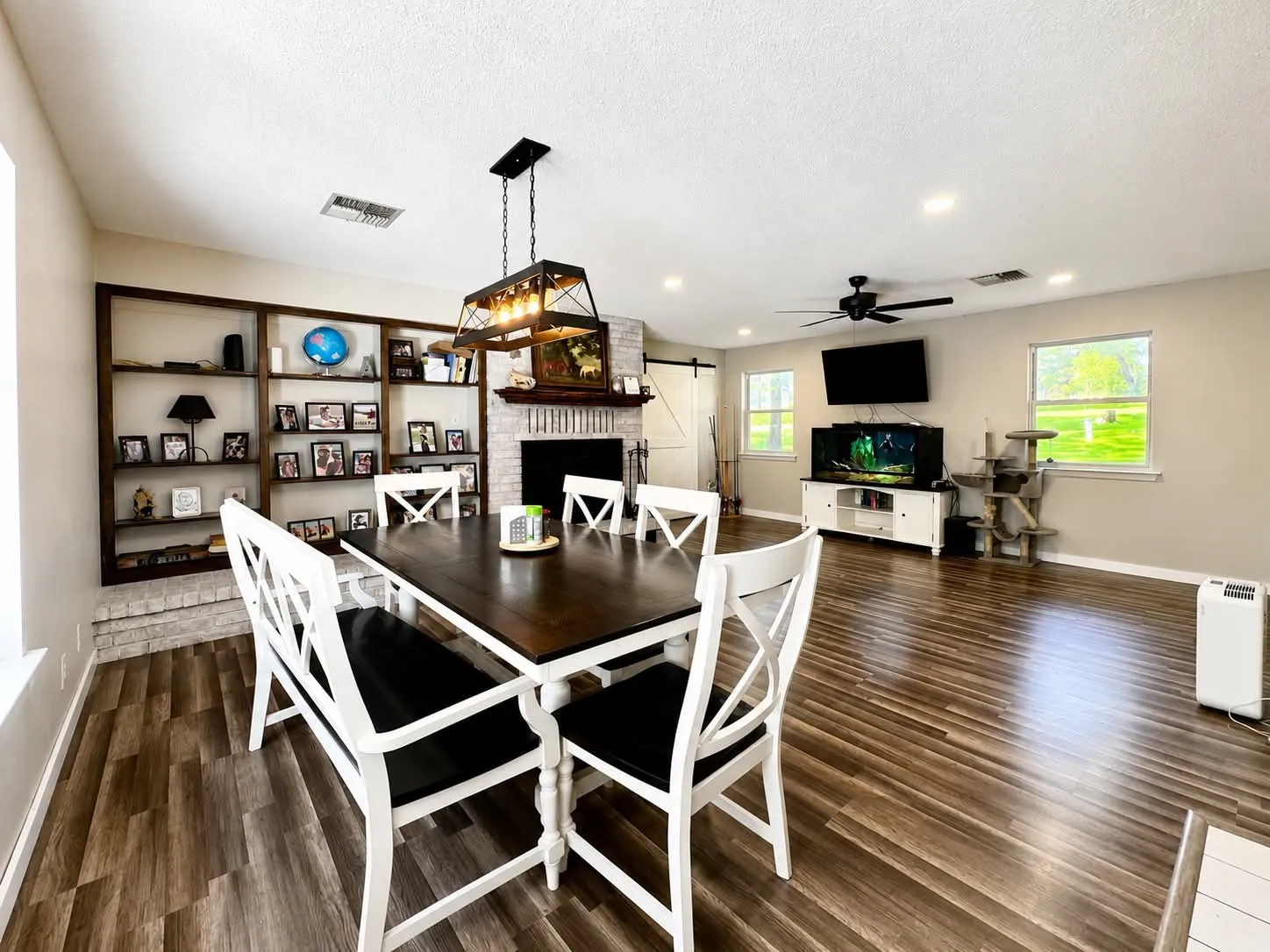 Open-concept living space featuring wood-finish flooring, recessed lighting, and a linear chandelier
