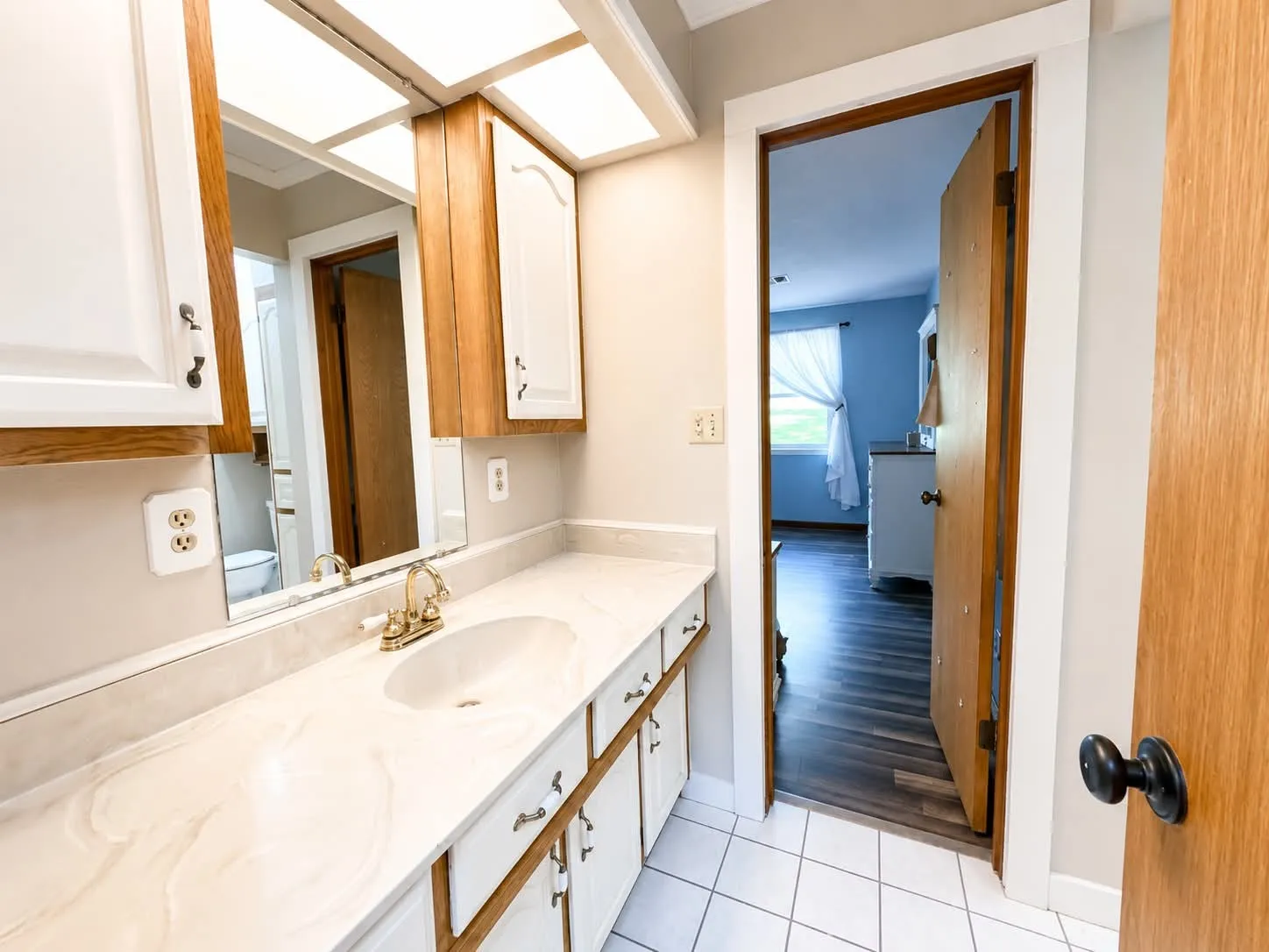 Bathroom vanity with a gold-tone faucet, integrated sink, and a large mirror
