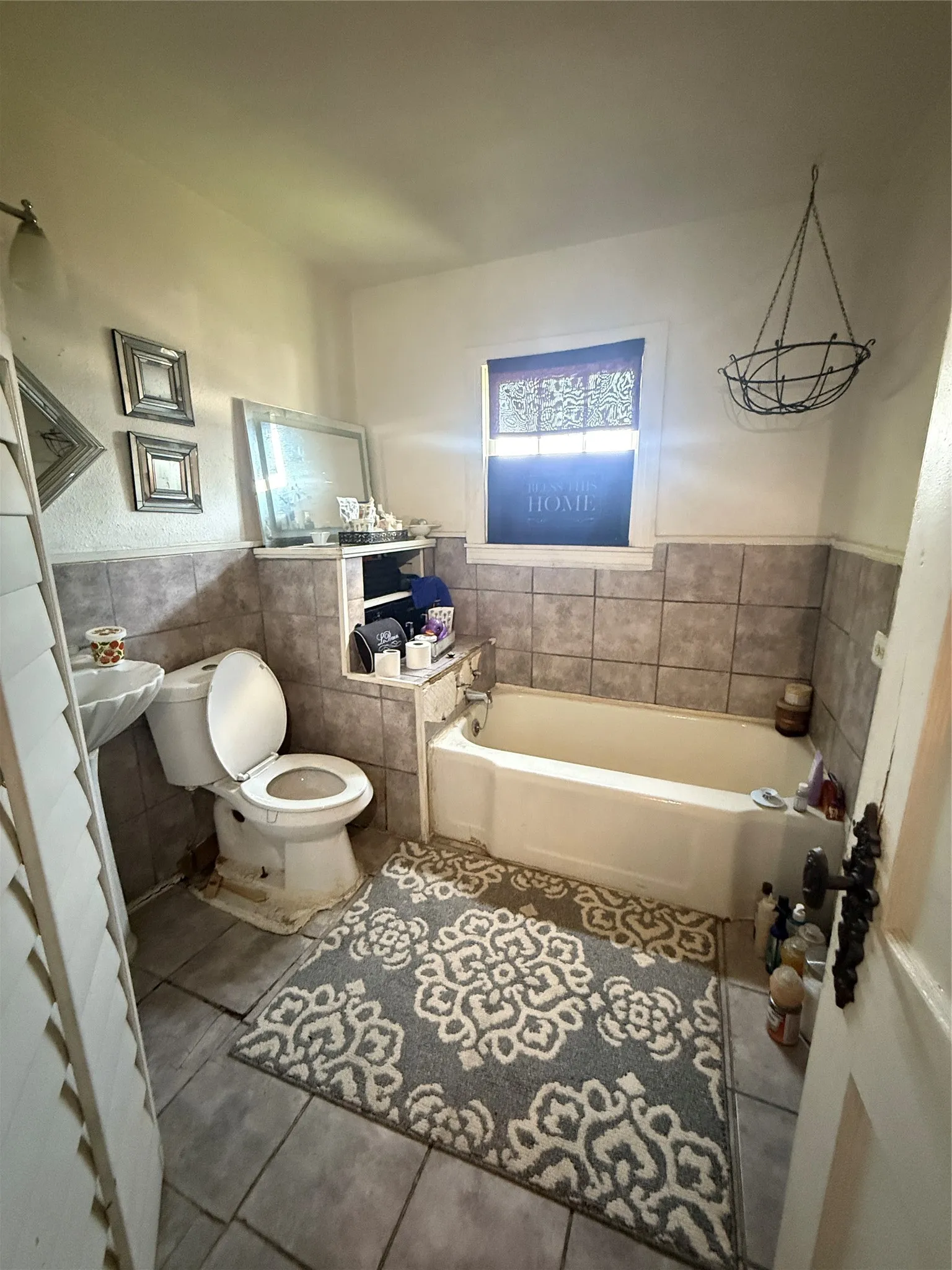 Bathroom featuring a built-in bathtub, a pedestal sink, and tiled flooring