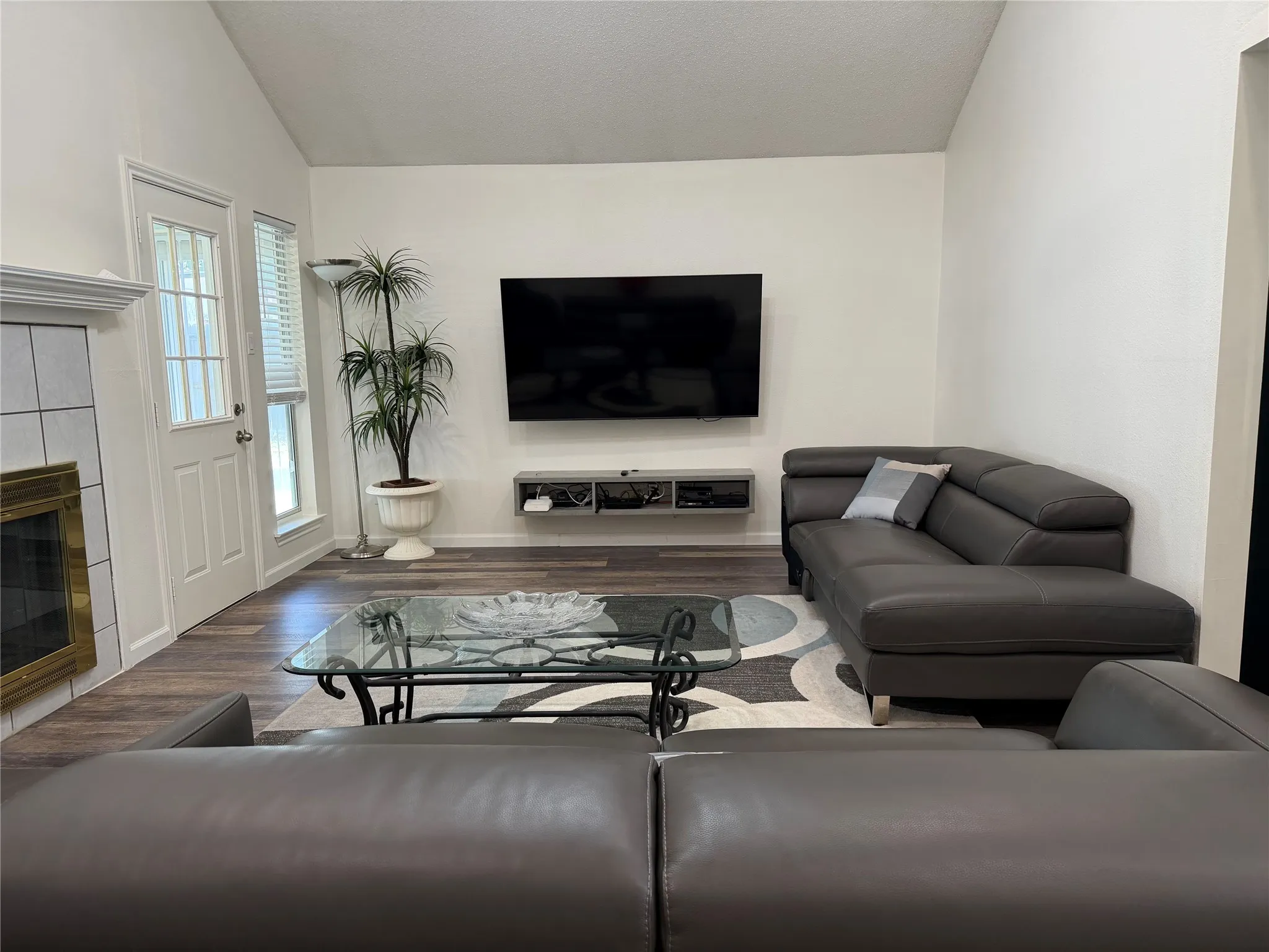 Spacious living area featuring a vaulted ceiling and wood-finish flooring