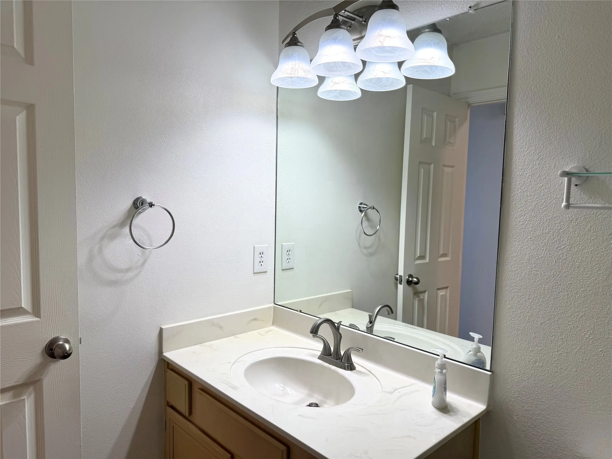 Bathroom vanity with a light wood-finish cabinet, integrated sink, and a light-colored countertop