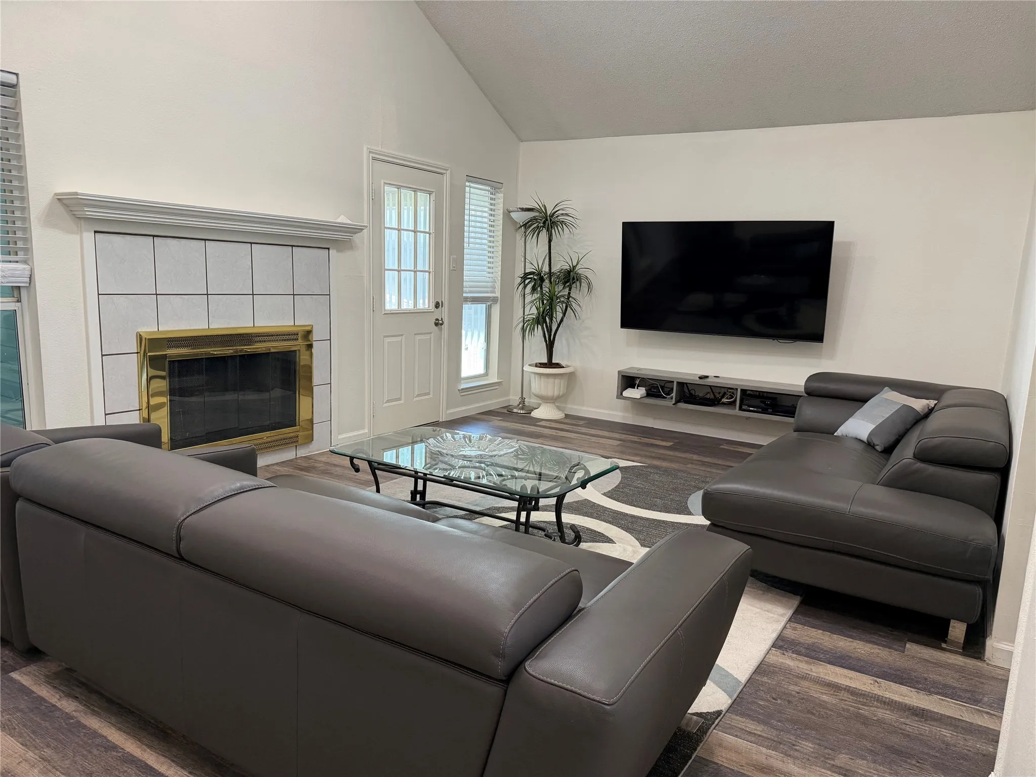 Spacious living area featuring a vaulted ceiling and wood-finish flooring