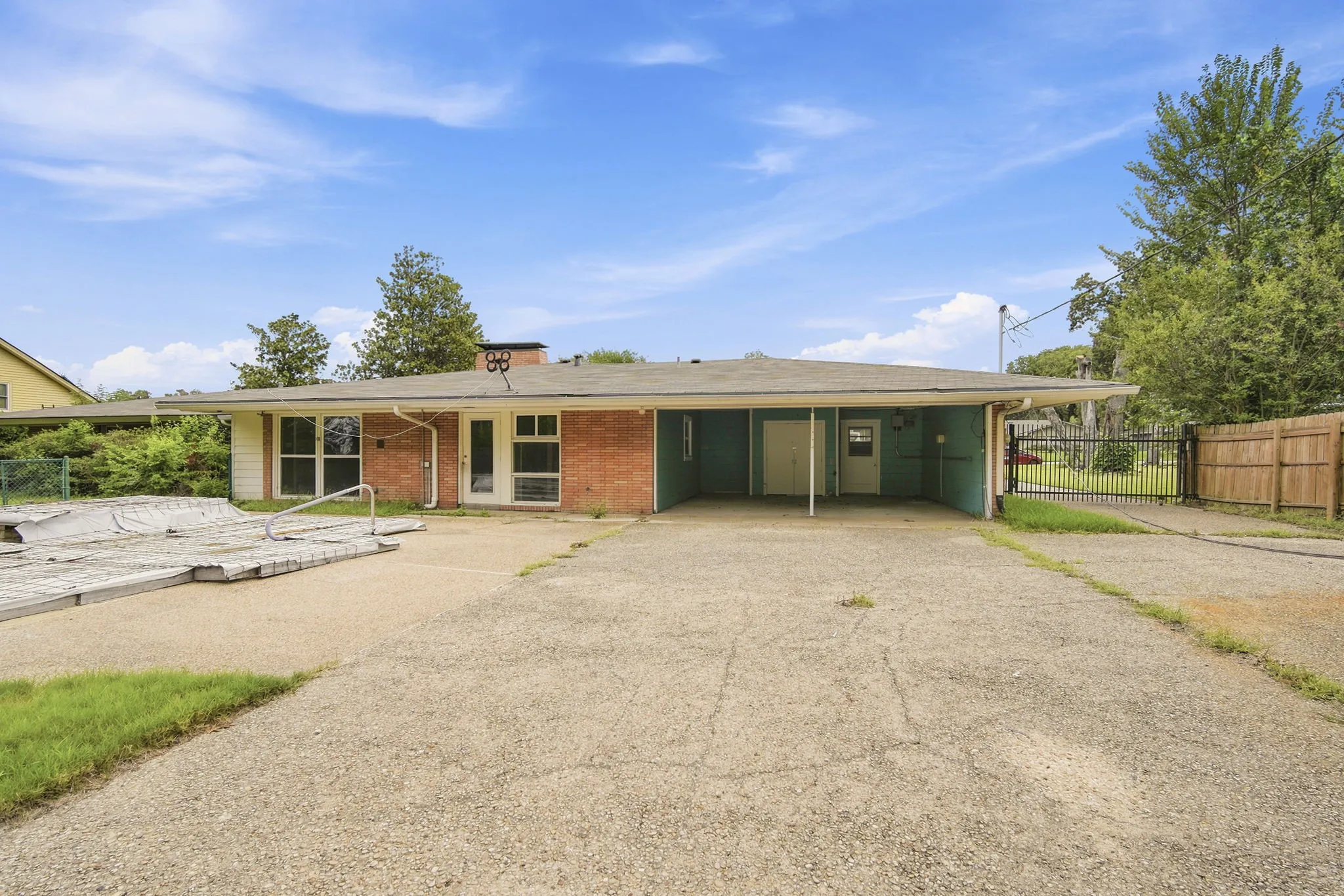 Ranch-style residence featuring a brick and painted siding exterior, a covered carport, and a rear patio area