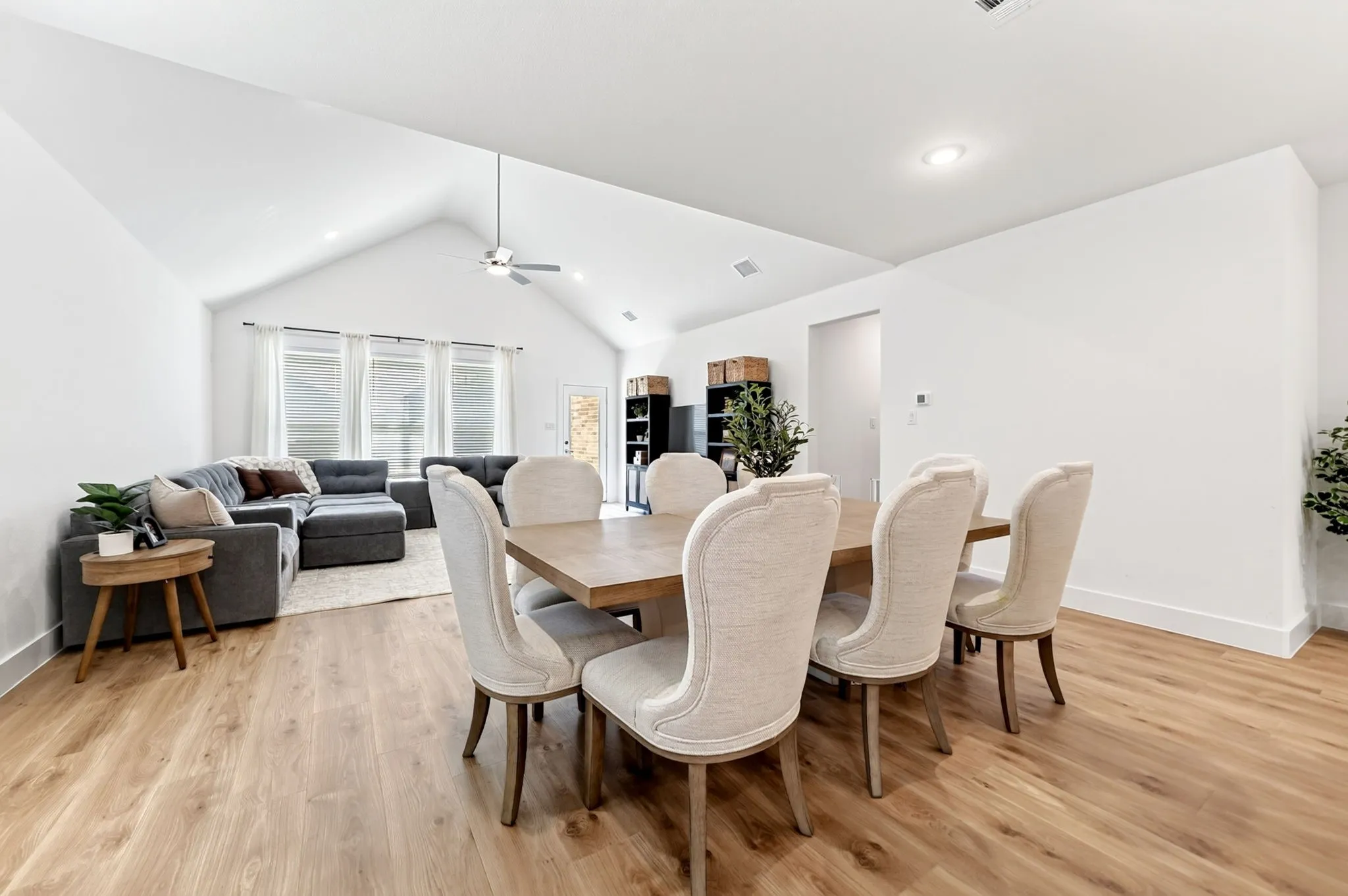 Open-concept living space featuring wood-finish flooring, a vaulted ceiling with a ceiling fan, and recessed lighting