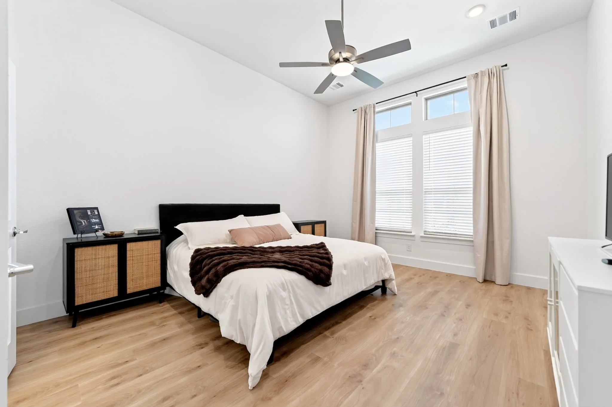 Room with light wood-finish flooring, white walls, and a vaulted ceiling