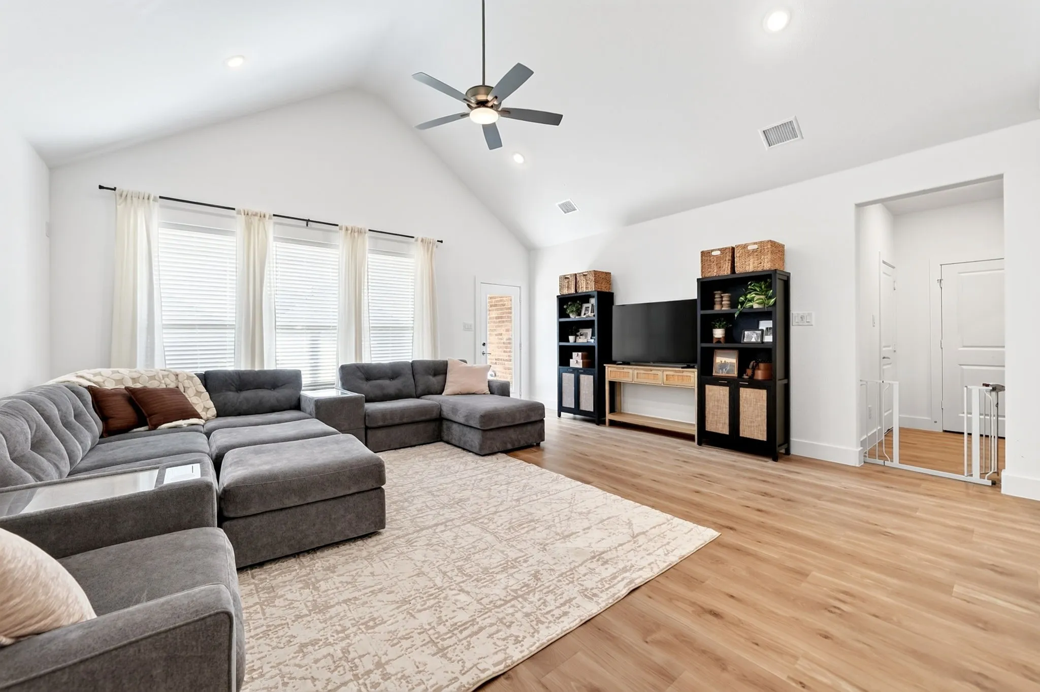 Spacious living area featuring a vaulted ceiling with a ceiling fan, recessed lighting, and light wood-finish flooring
