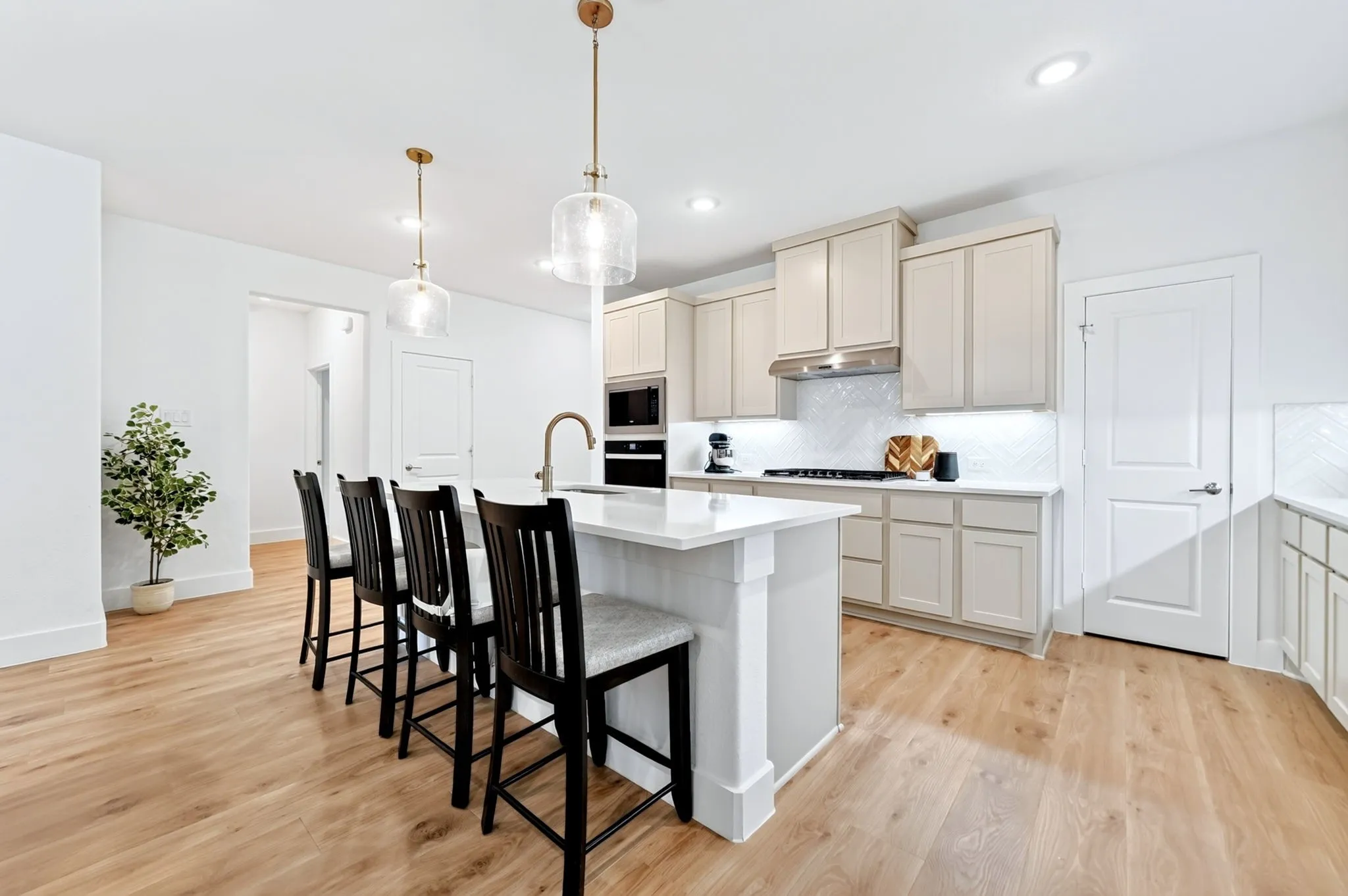 Kitchen featuring a large island, wood-finish flooring, recessed lighting, pendant lights, and light-toned cabinetry