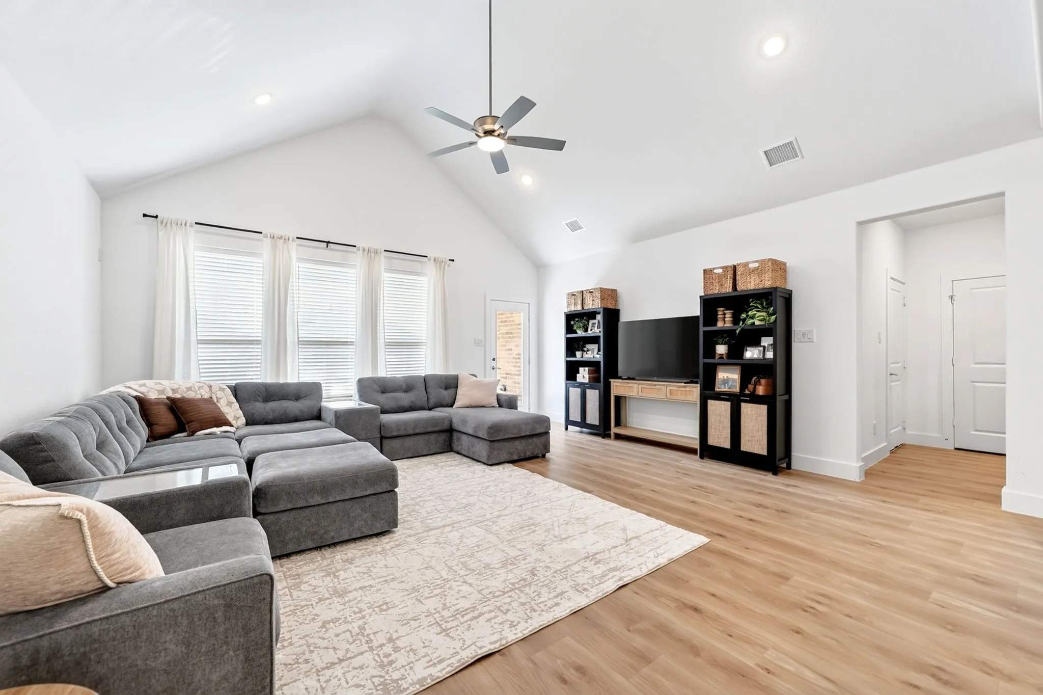 Spacious living area featuring a vaulted ceiling and contemporary ceiling fan