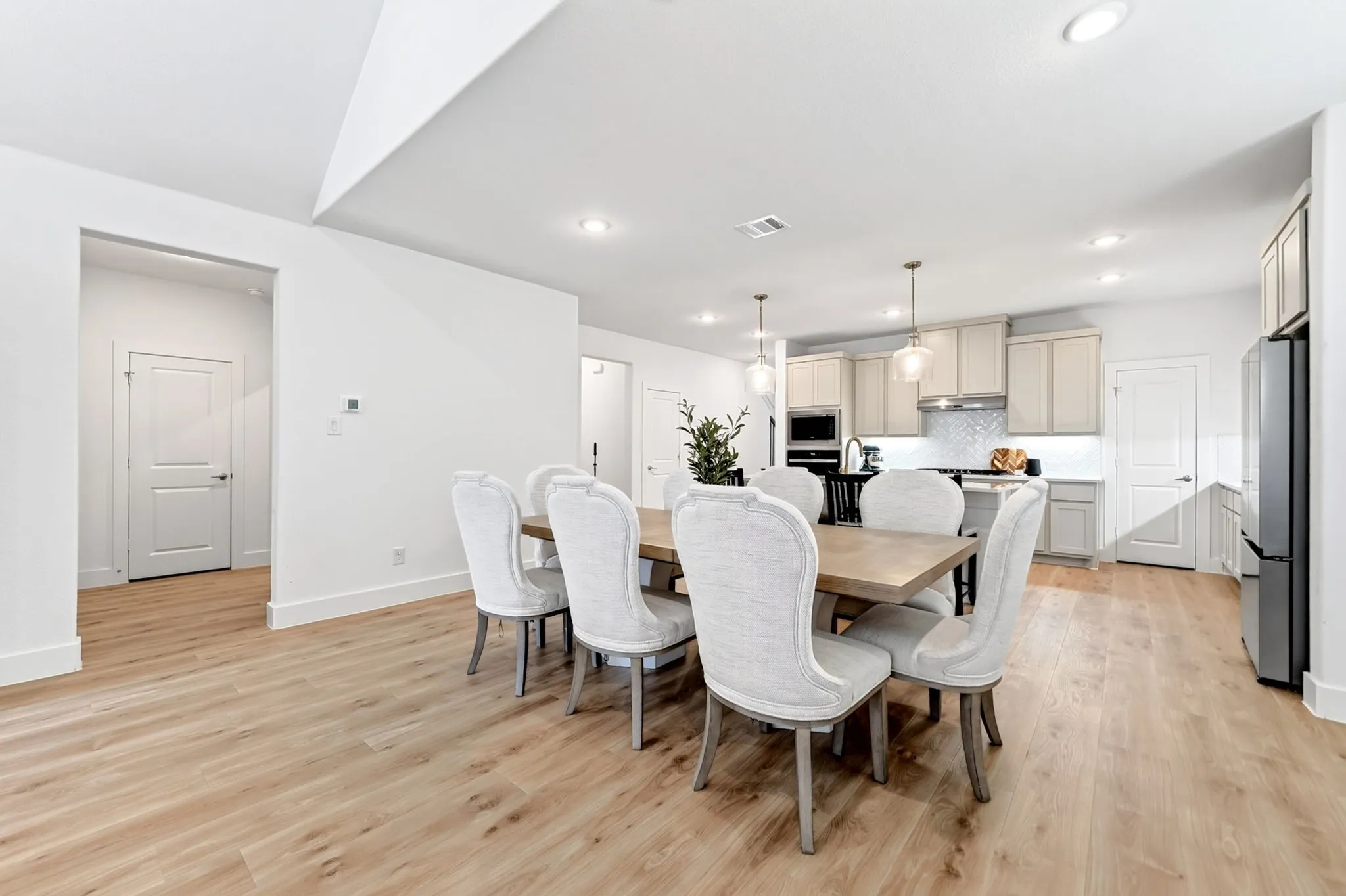 Open-concept dining area featuring wood-finish flooring, recessed lighting, and a white baseboard trim