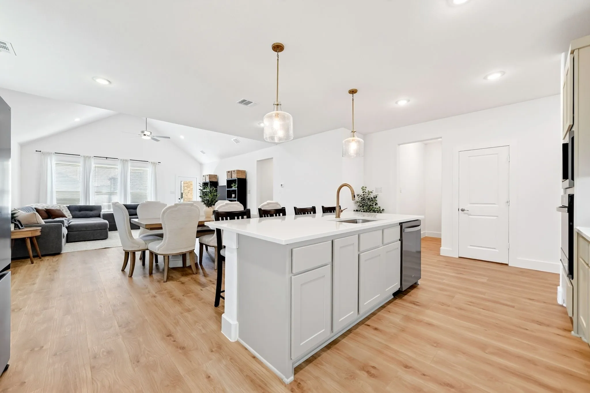 Open-concept kitchen featuring a center island with sink and pendant lighting