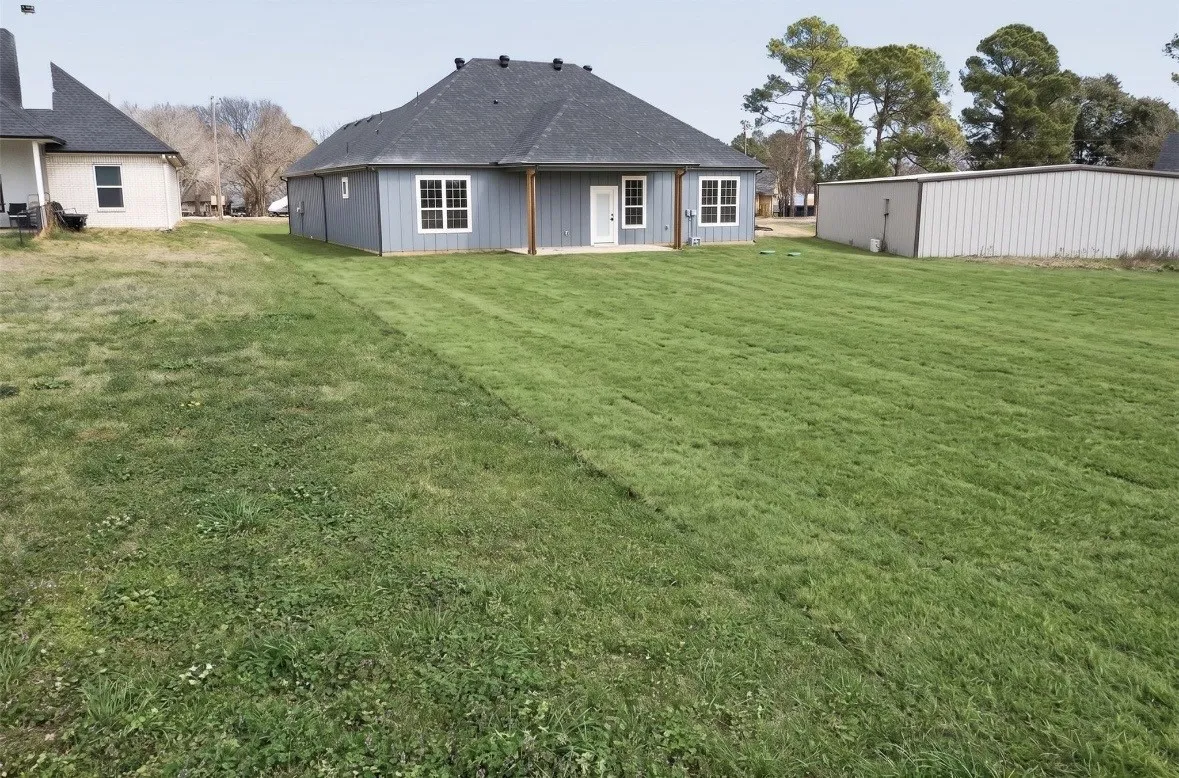 Spacious rear yard with a well-maintained lawn and a blue-sided residence