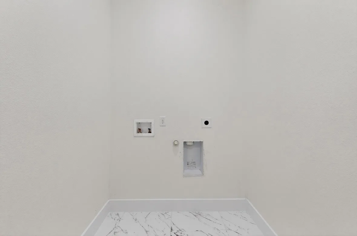 Dedicated laundry space featuring white textured walls and marble-look tile flooring
