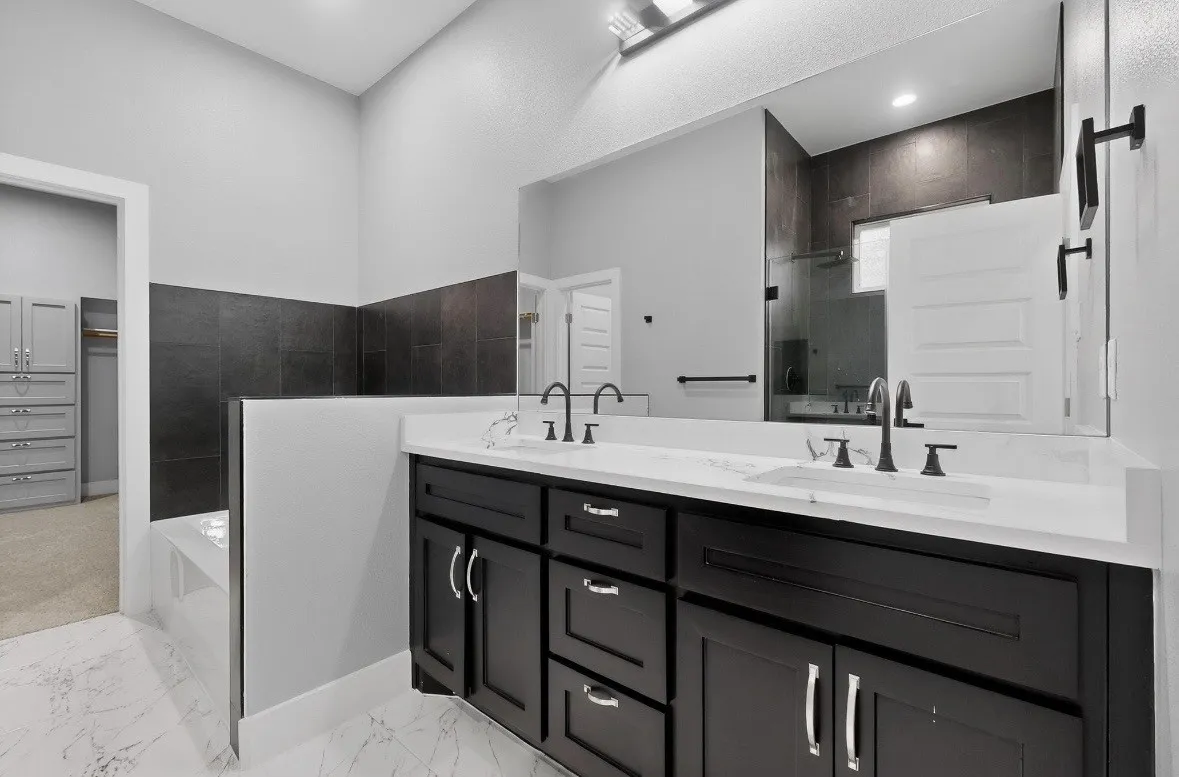 Bathroom vanity featuring dual under-mount sinks, white countertops, and dark wood-finish cabinetry with brushed nickel hardware