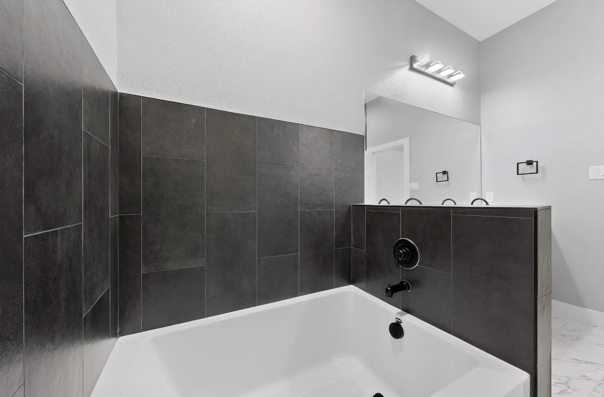 Built-in white soaking tub featuring matte black fixtures