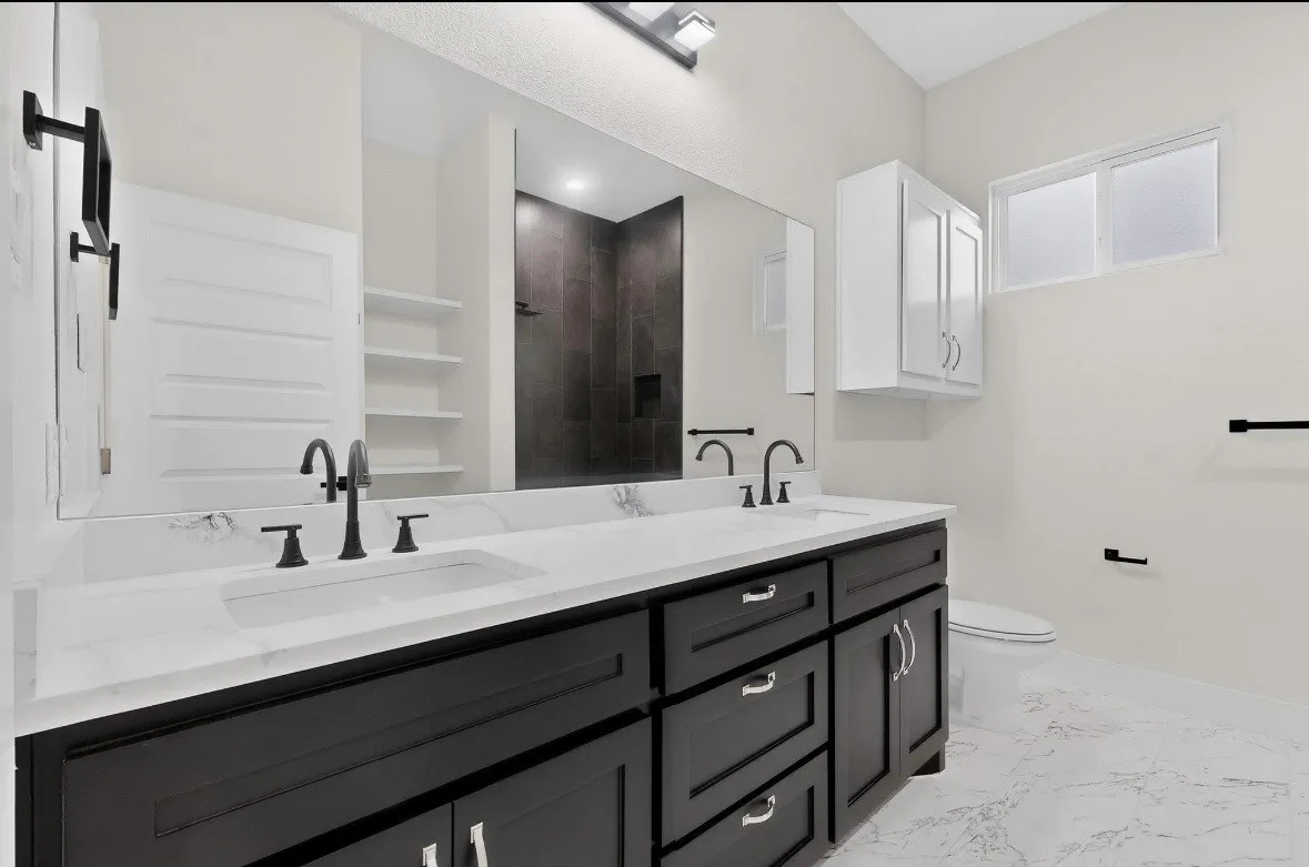 Double vanity with dark wood cabinetry, white countertops, and matte black hardware