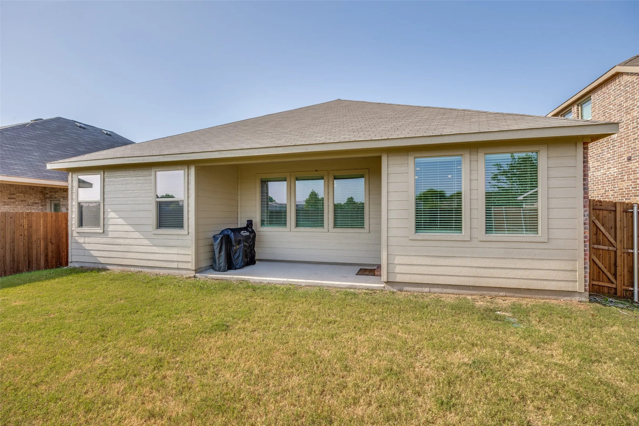 Expansive backyard with a manicured lawn, a covered concrete patio, and a privacy fence